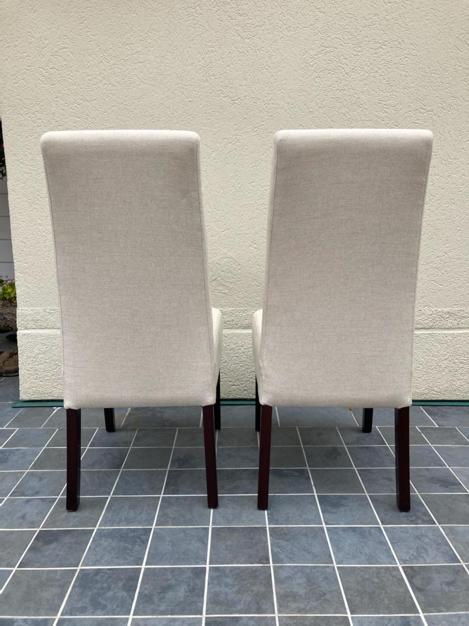 Impressive pair of Parsons style dining chairs by Palecek 
featuring upholstered seat and back in oatmeal colored linen fabric with mahogany legs.