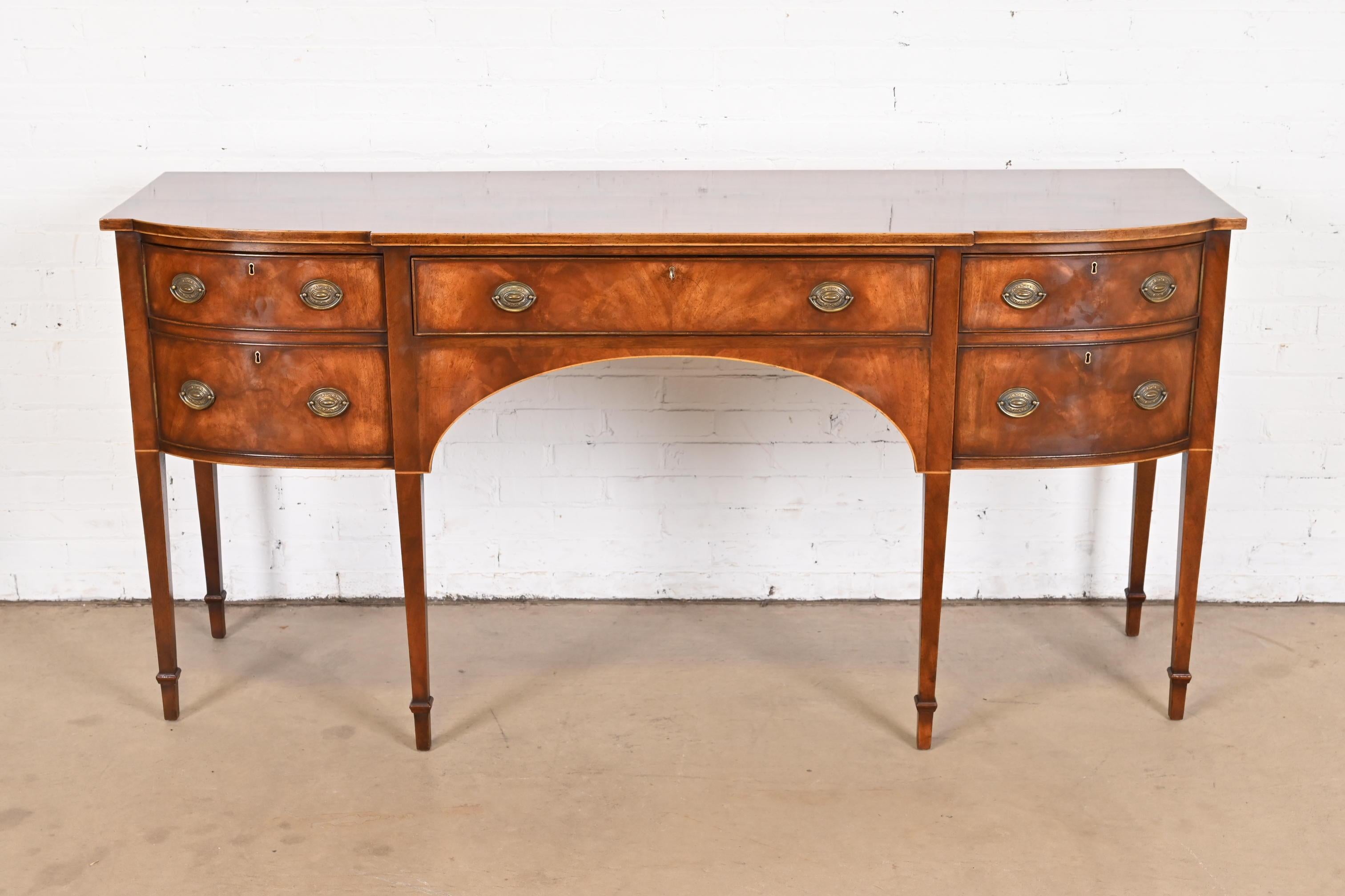 A gorgeous Hepplewhite or Federal style sideboard buffet or credenza

By Smith & Watson

USA, Late 20th Century

Gorgeous flame mahogany, with satinwood string inlay, and original brass hardware.

Measures: 72