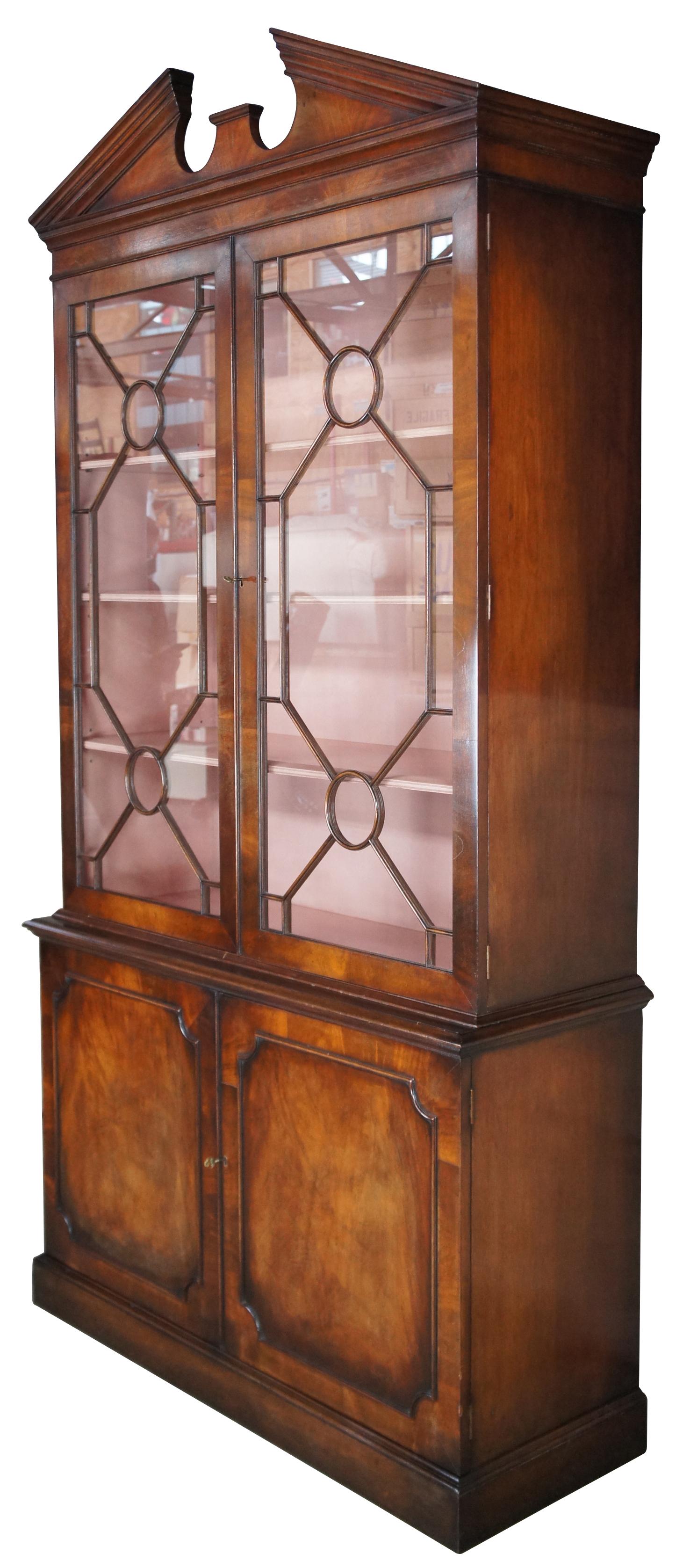 Smith & Watson Georgian bookcase or display cabinet, circa last quarter 20th century. Made from flamed mahogany with a larger upper display section featuring applied fretwork over lower concealed storage. Crown fashions a broken arch pediment.