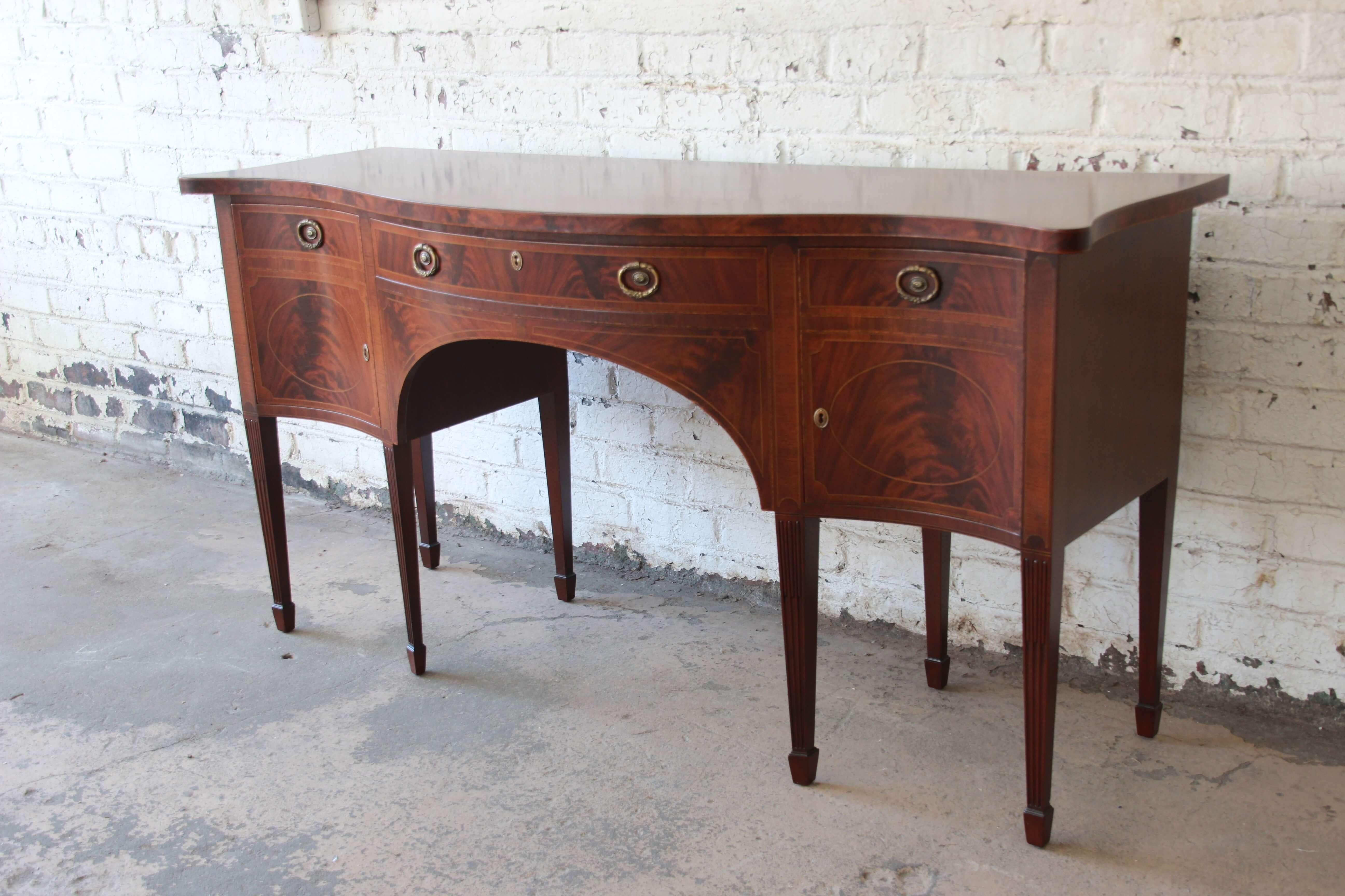 Offering a beautiful inlaid flame mahogany sideboard buffet by Smith & Watson Cabinet Makers. This crafted Federal style reproduction has nice inlayed edging on the top, banded edges, and stunning flame mahogany making this statement piece prominent