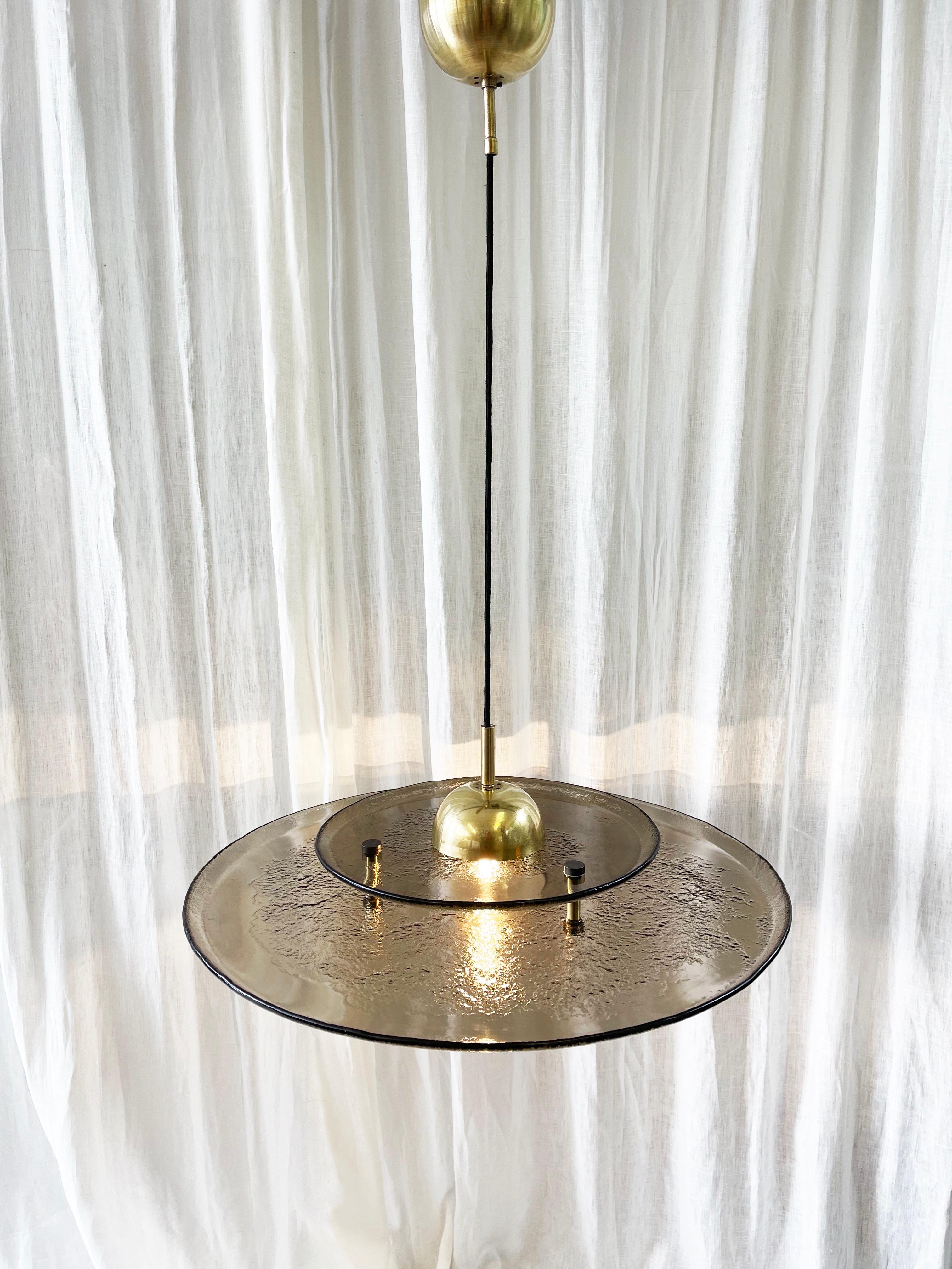 Beautifully designed pendant lamp from the 1980s, attributed to the late 1970's to 1980's.
Fantastic design in most likely Murano ice glas in a smoky greyish brown.
Two disks layered in thick chunky glas which is only partially 'ice'-frosted.

ø of