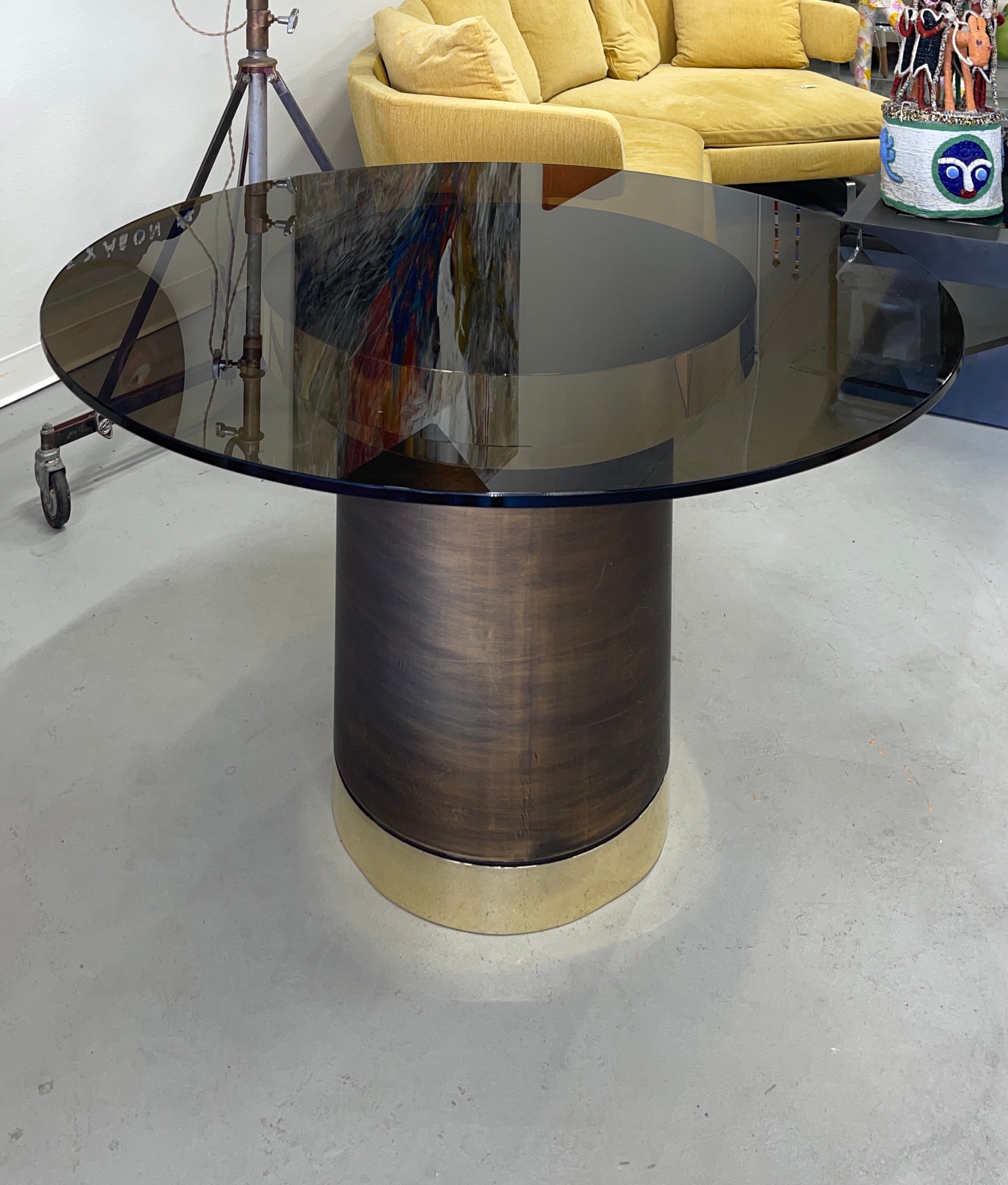 An unusual table with a bronze colored smoky top. The base has polished base top and base with a center of brushed brass. Very much in the style of some Karl Springer designs we’ve seen over the years. We had the brass polished out to a nice shiny