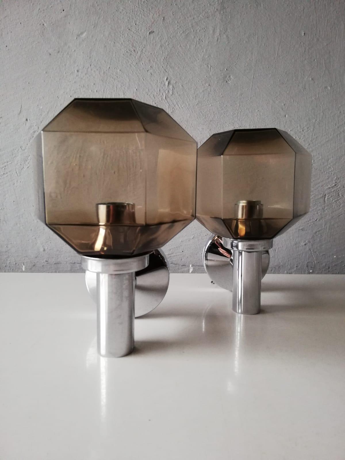 Smoke glass and chrome body sconces by Hillebrand, 1960s Germany

Very nice high quality wall lamps.

Lamps are in very good vintage condition.

These lamps works with E14 standard light bulbs. 
Wired and suitable to use in all countries.