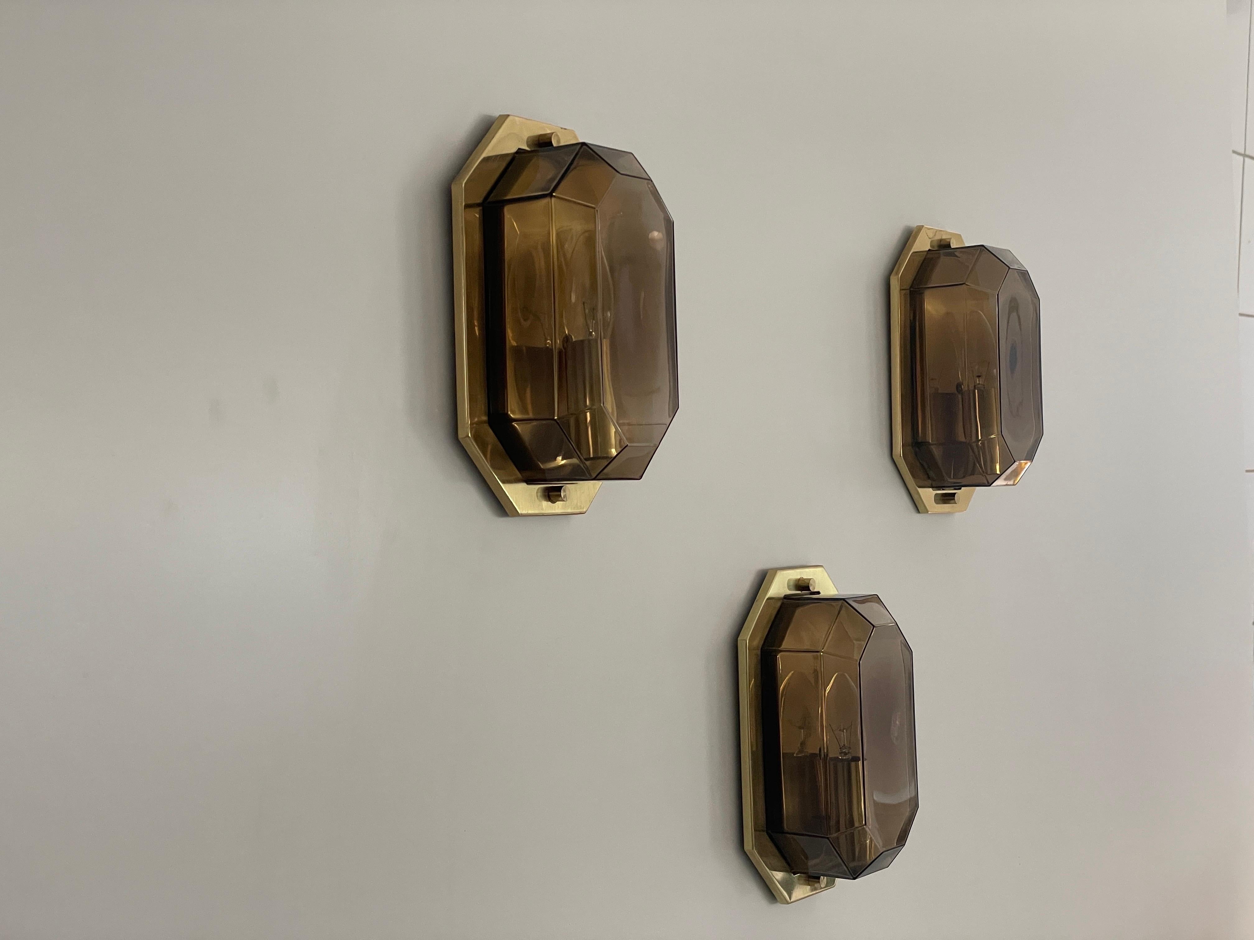 Juego de 3 apliques de cristal ahumado y latón de Limburg, años 60, Alemania
Apliques muy bonitos y de gran calidad.

Las lámparas están en muy buen estado vintage.


Estas lámparas funcionan con bombillas estándar E14. 
Con cable y apto para su uso