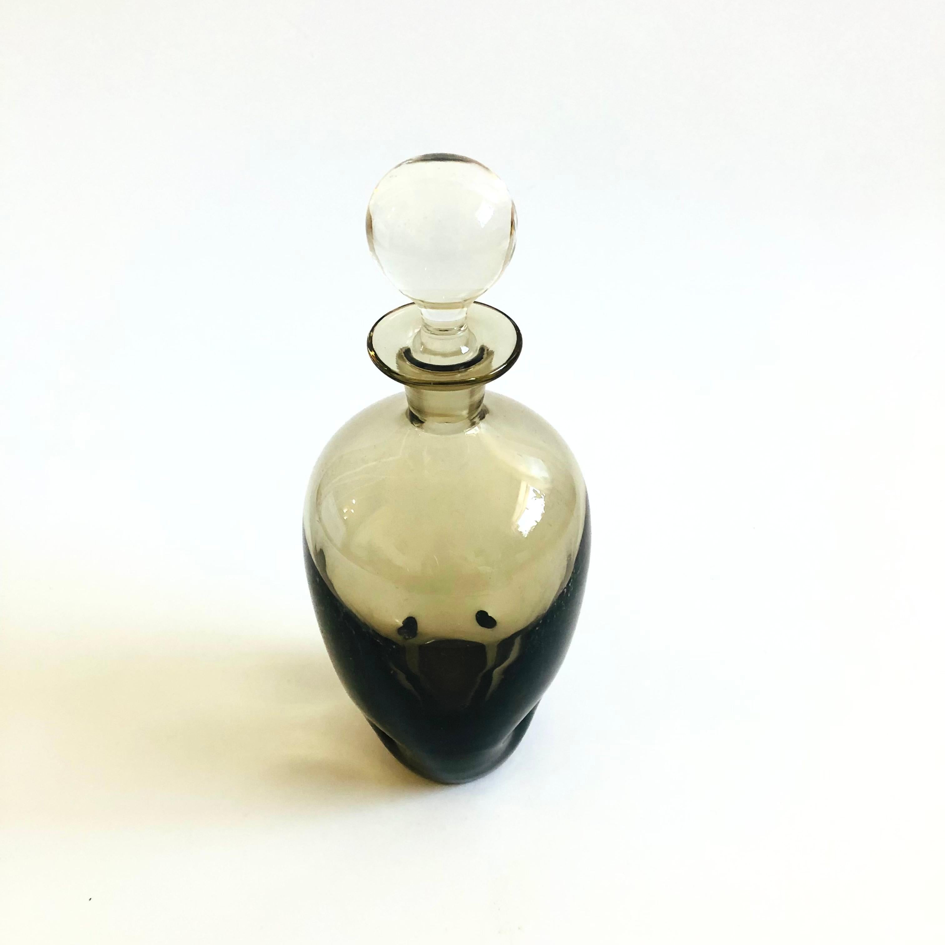 A vintage glass decanter. Beautiful moody gray color to the glass with a clear round glass stopper. Made a blown glass with beautiful dimpling to the base.

