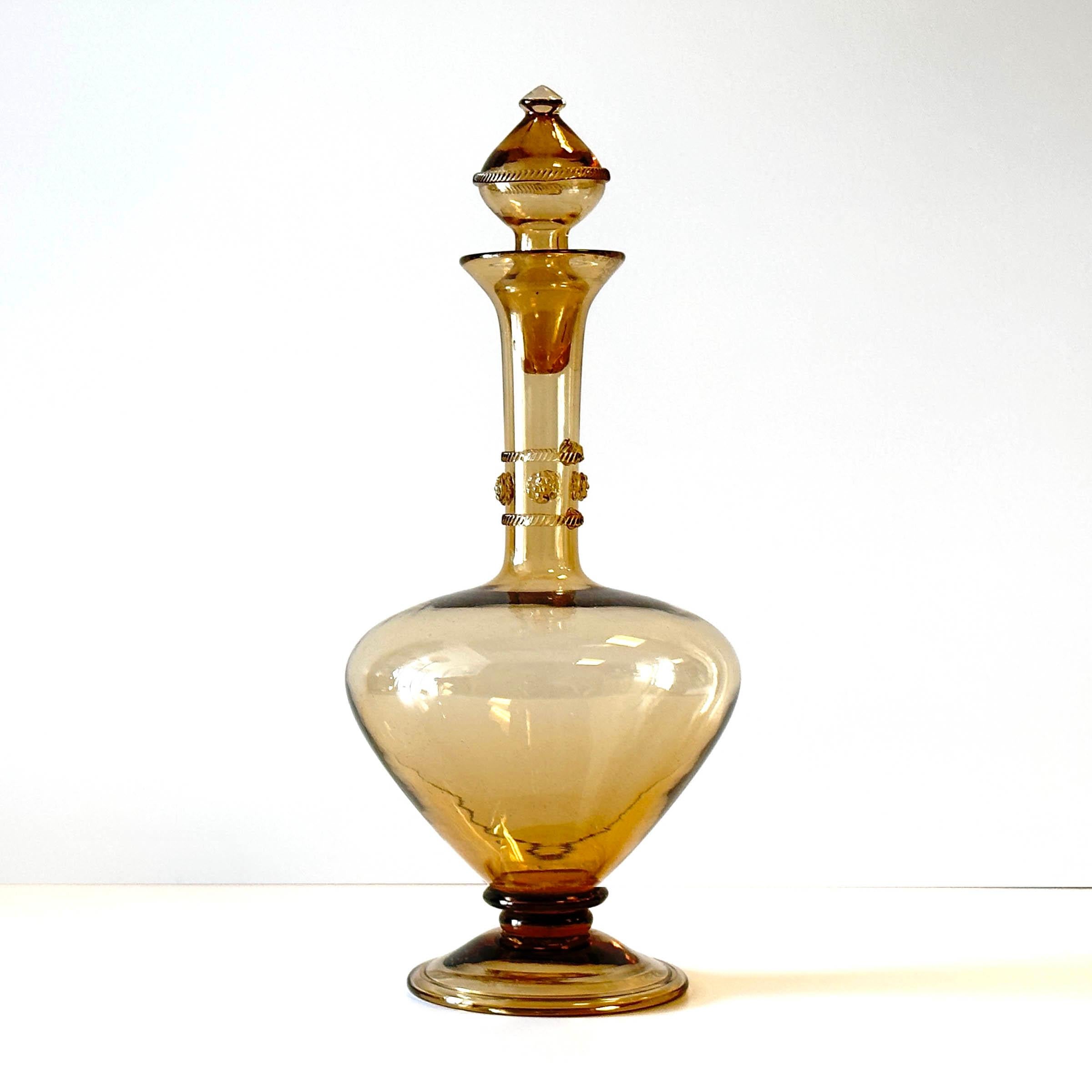 A fine example of a blown glass footed decanter with applied decoration in the style associated with designs from the Czech Republic in the early 20th Century. The angular stopper has decoration too. Nice touch. It is 13 inches tall. No visible