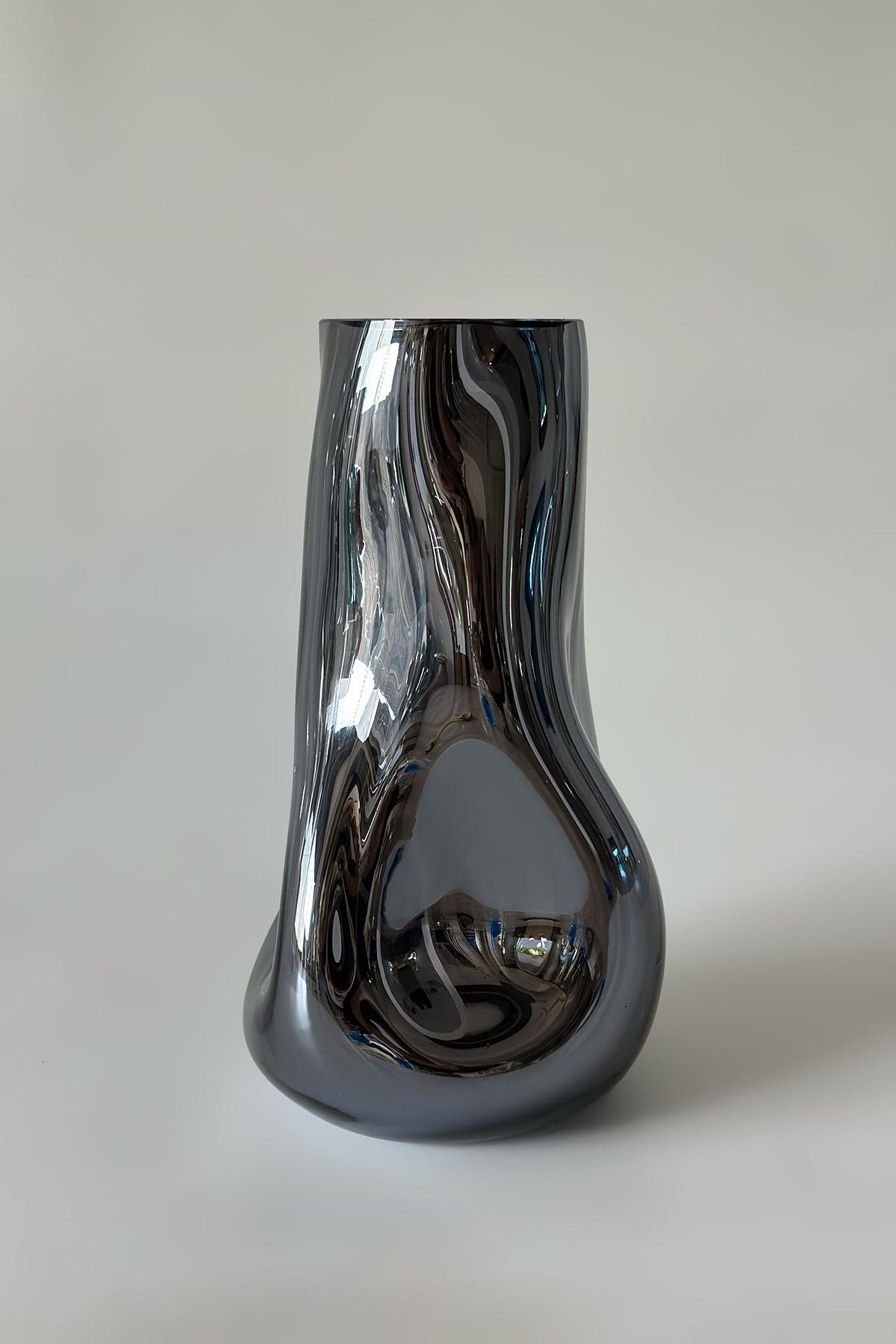 Vaso Smoke Wave di Homa
Dimensioni: L 20 x P 24 x H 38 cm
Materiali:  Vetro soffiato. Silver Mirror. 

HOMA è un atelier di design contemporaneo con sede a Istanbul. I processi caratteristici dell'Atelier sono il vetro soffiato a mano, la