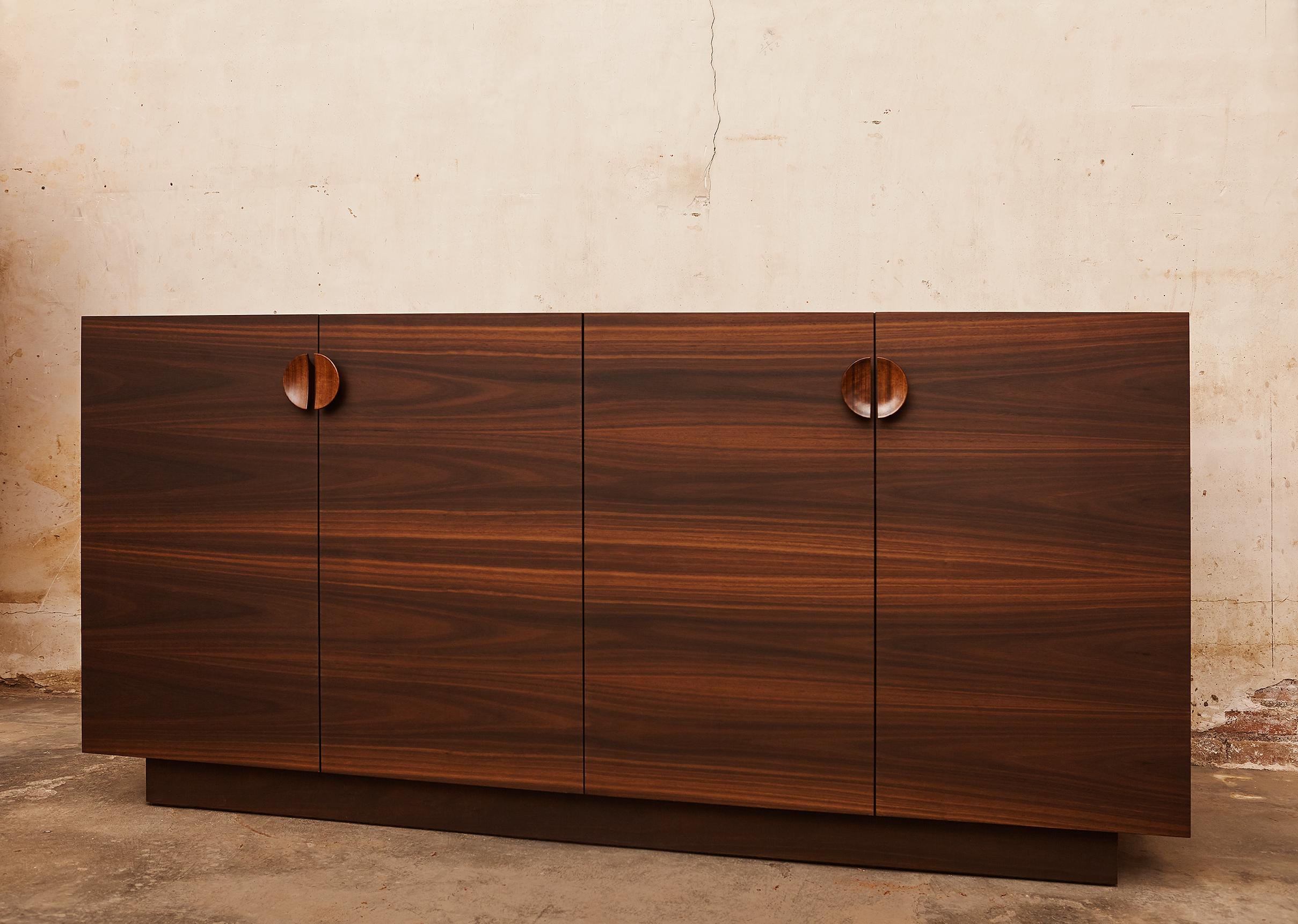 This Italian designed contemporary sideboard has 4 book matched eucalyptus wood doors with ample storage which can be customized. The doors featured turned wood pulls. 

The inside was finished with contrasting Brazilian etimoe wood shelving. The