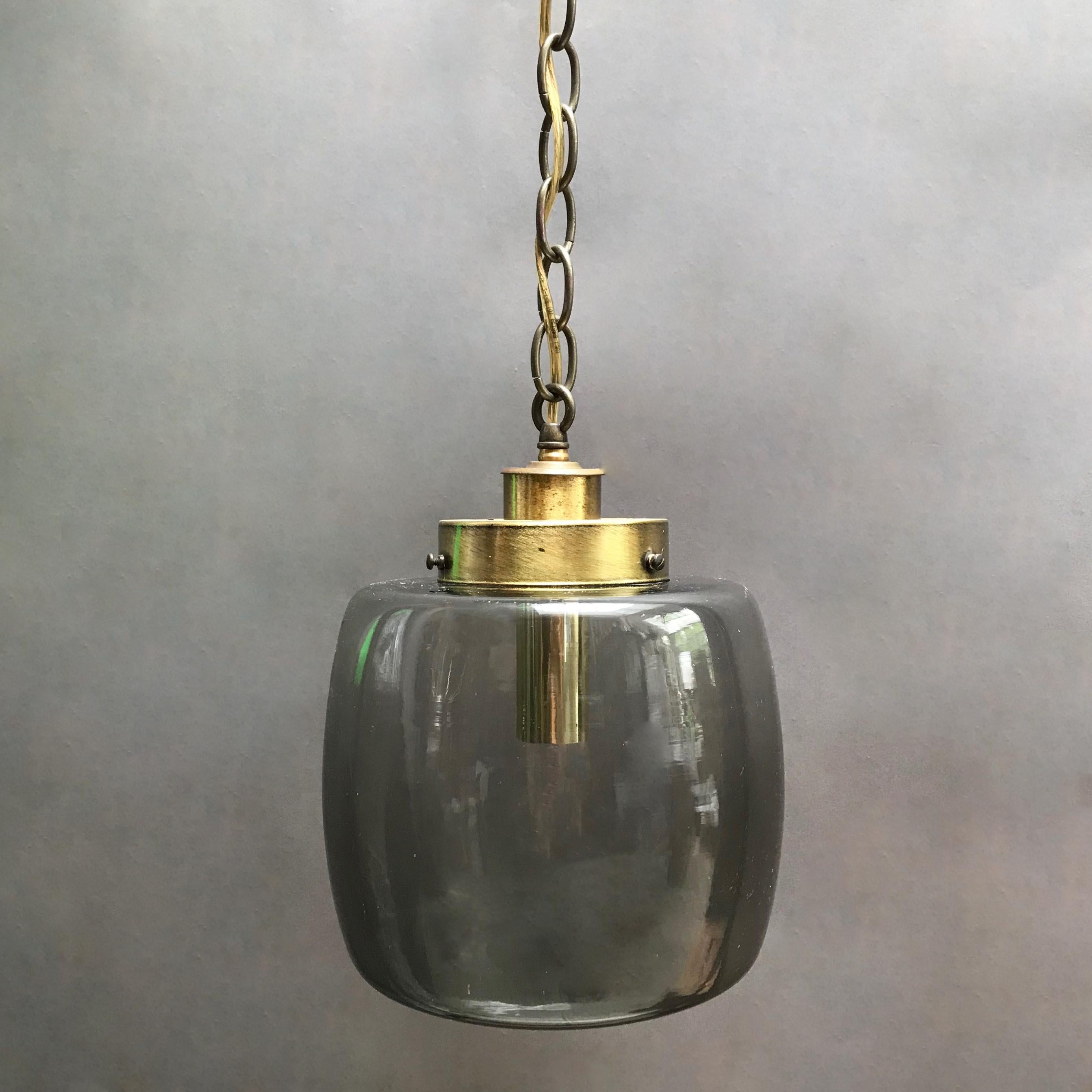 Mid-Century Modern, pendant light features a smoked glass closed lantern shade with brass fitter and 44 inches of brass chain wired to accept up to 150 watt bulb.