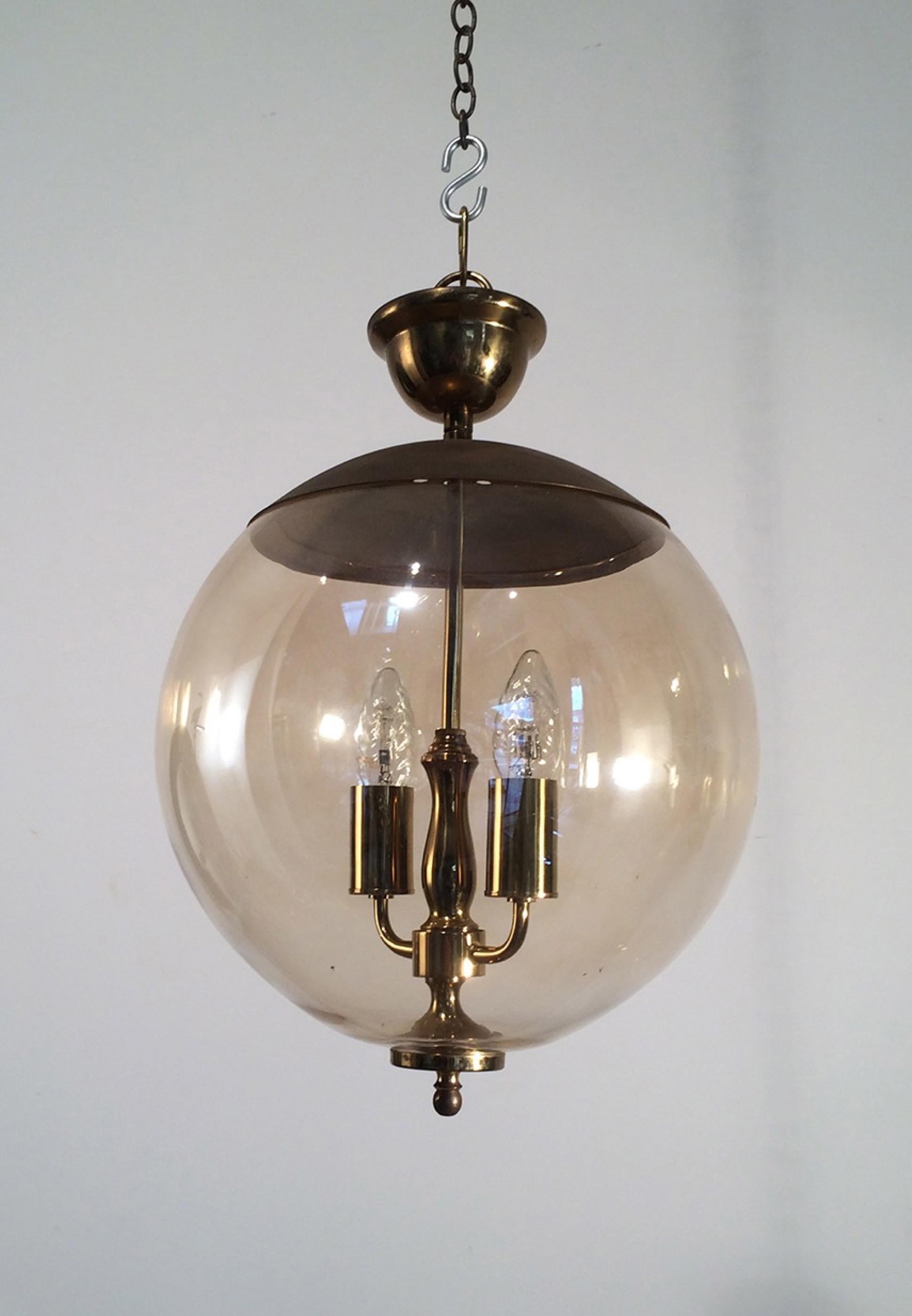 This Unusual fixture is made of a smoked glass ball including a brass double light with brass top and finial on the bottom. This is a French work, circa 1970.