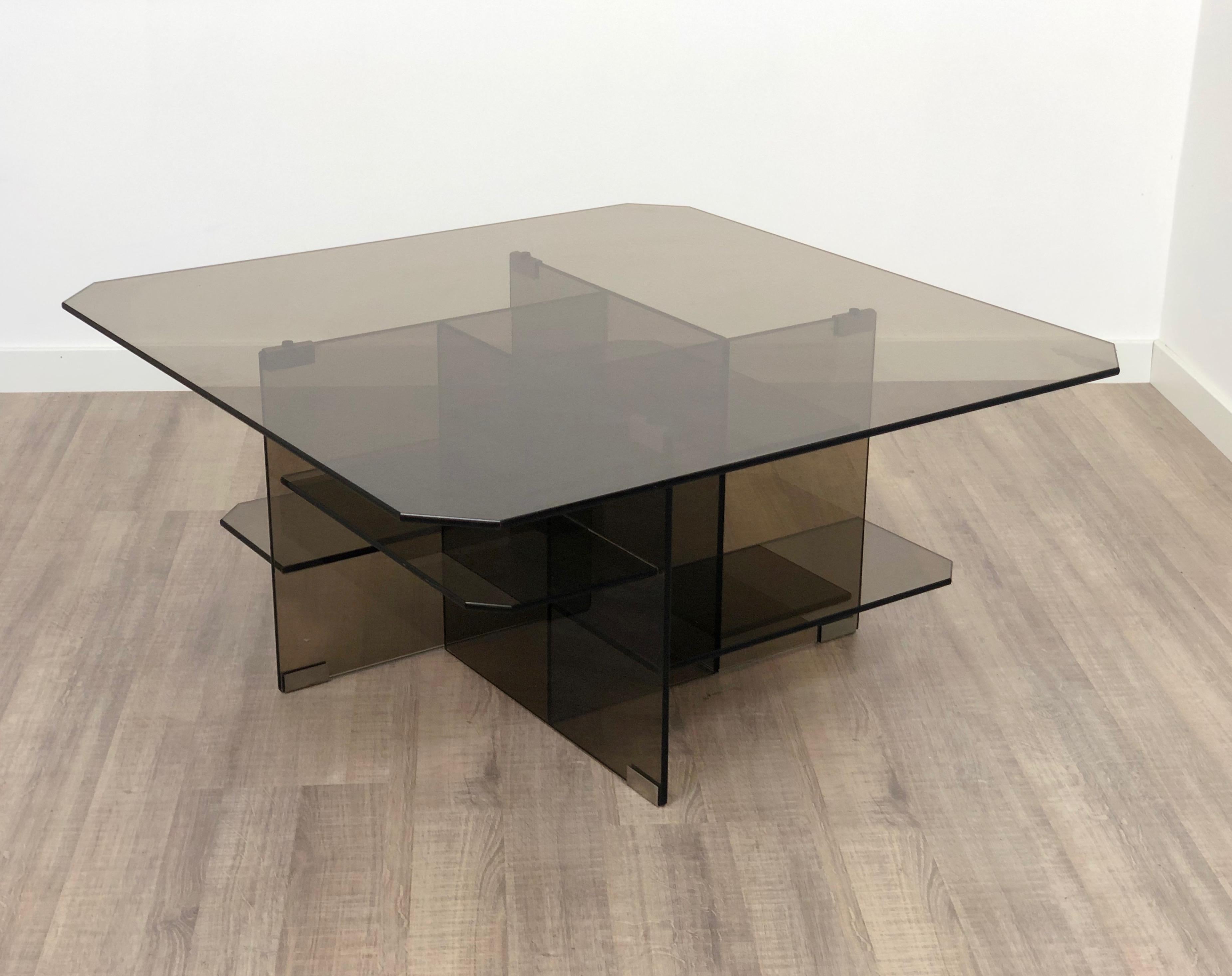 Table basse/latérale entièrement en verre fumé avec une présence sculpturale abstraite qui lui confère un style dynamique.
