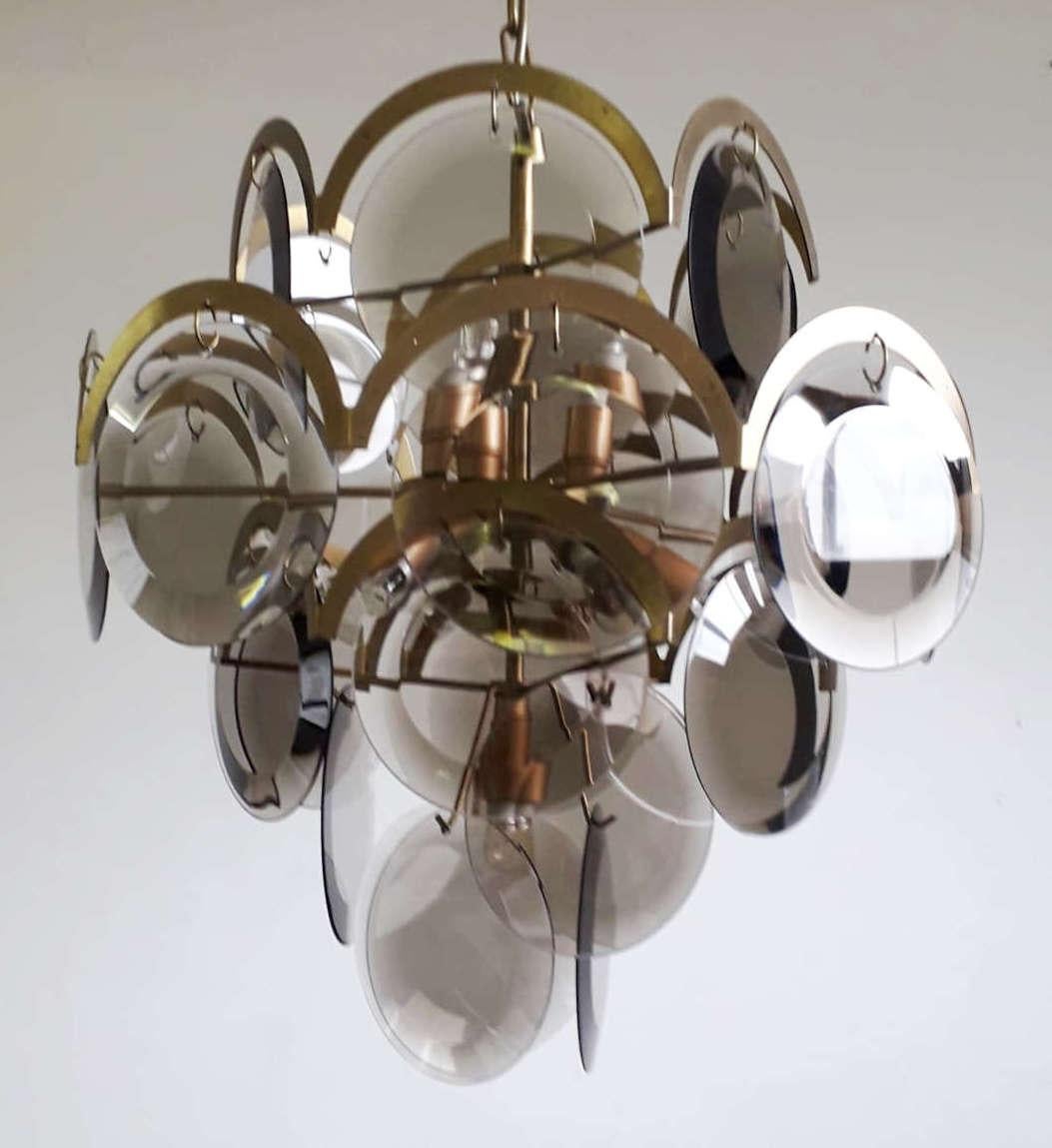 Vintage Italian chandelier with five tiers of smoky beveled glass discs mounted on brass frame, with a half moon brass arch above each disc / Designed and made by VIstosi in Italy, circa 1960s
10 lights / E12 or E14 / max 40W each
Measures: diameter