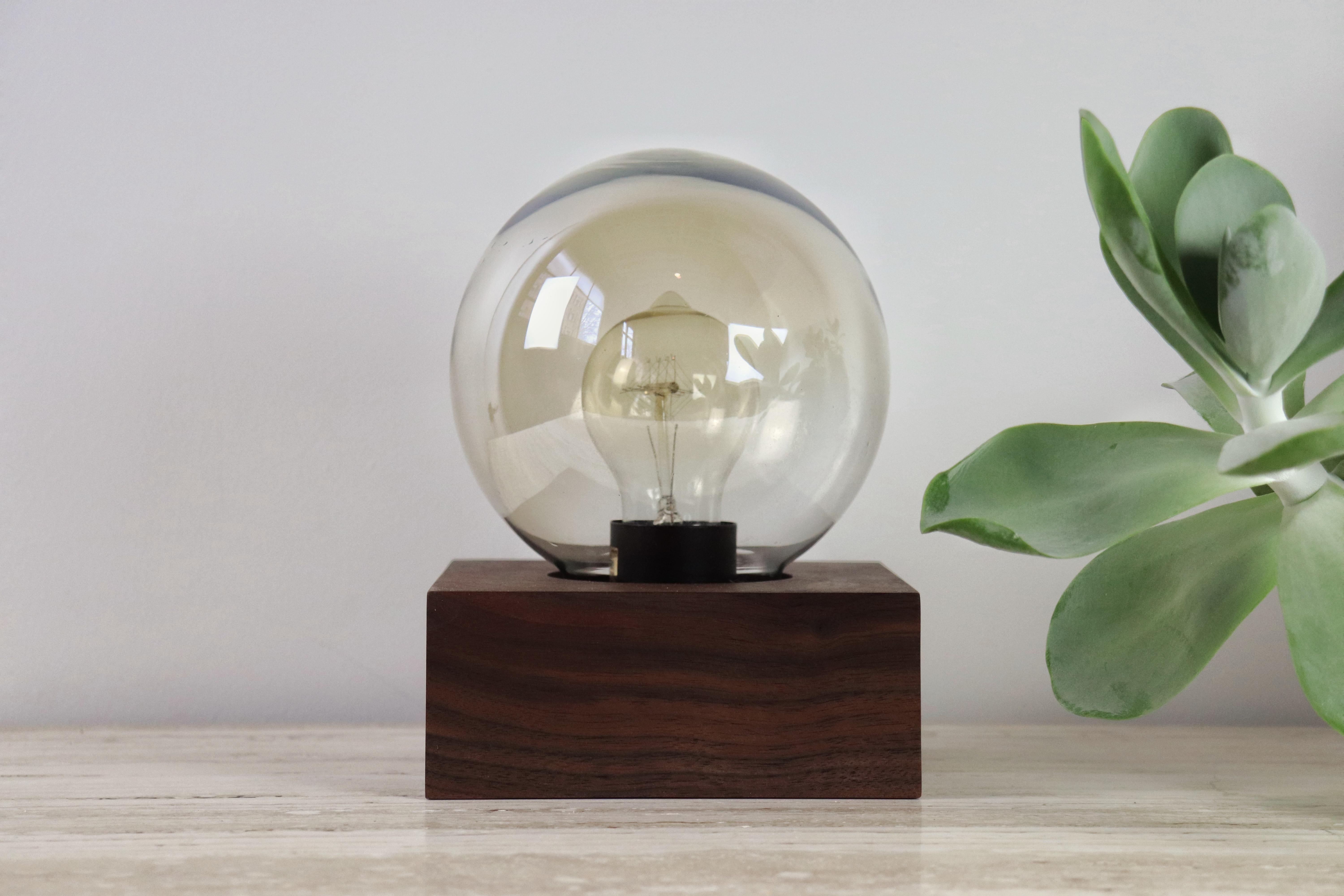 Timeless and beautiful, this lamp has a smoked or white glass globe and is made in Material's Portland workshop.  Shown with hand oiled Oregon Black Walnut base, black cloth cord (with thumb switch), and 2700K LED filament bulb. Works particularly