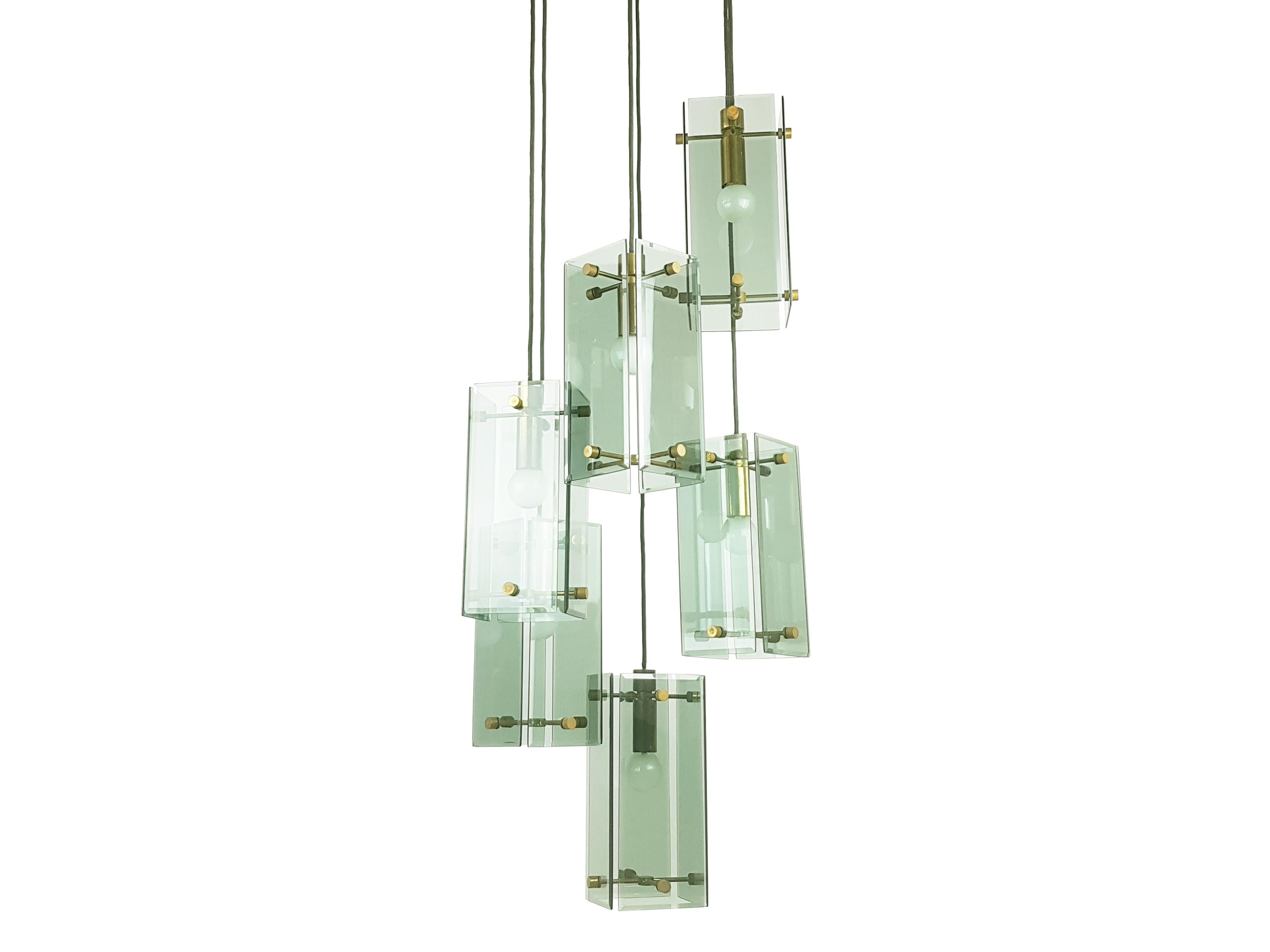 Diese elegante Lampe wurde um die 1960er Jahre in Italien hergestellt. Er besteht aus 6 Pendelleuchten in verschiedenen verstellbaren Höhen. Jedes Element besteht aus einer Messingstruktur mit 4 Rauchglasschirmen. Deckendecke aus Teakholz und