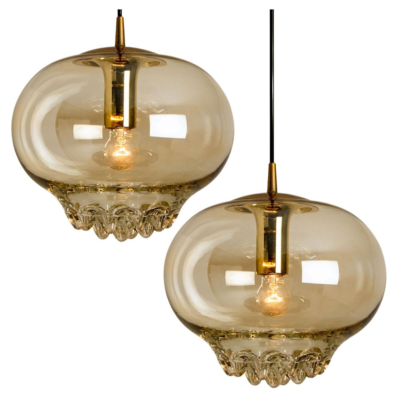 Paire de lampes suspendues dorées/brunes fumées, années 1960 par Peill et Putzler. Une forme unique et un merveilleux effet lumineux grâce à de jolis éléments en verre. Pièces de haute qualité. Illumine magnifiquement. Un véritable artisanat du 20e