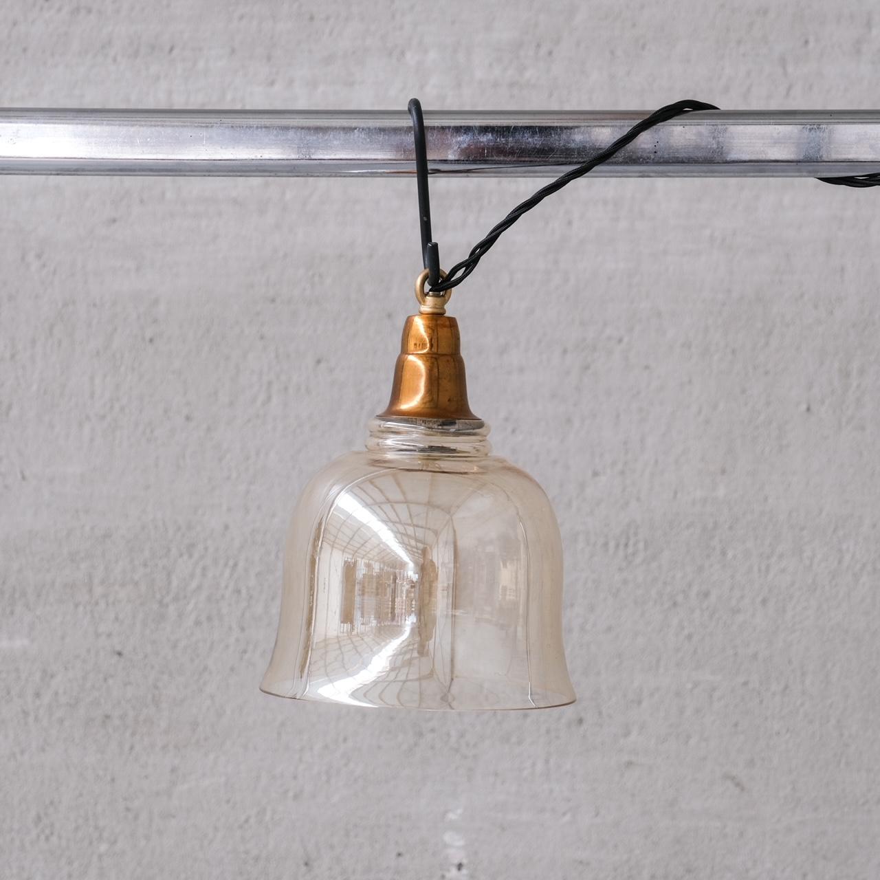 Brass slightly smoked glass pendant lights in bell shaped form.

Open bases.

France, c1960s.

5 available at the time of listing.

PRICED AND SOLD INDIVIDUALLY.

Re-wired and PAT tested.

No chain or ceiling rose was retained, we can recommend