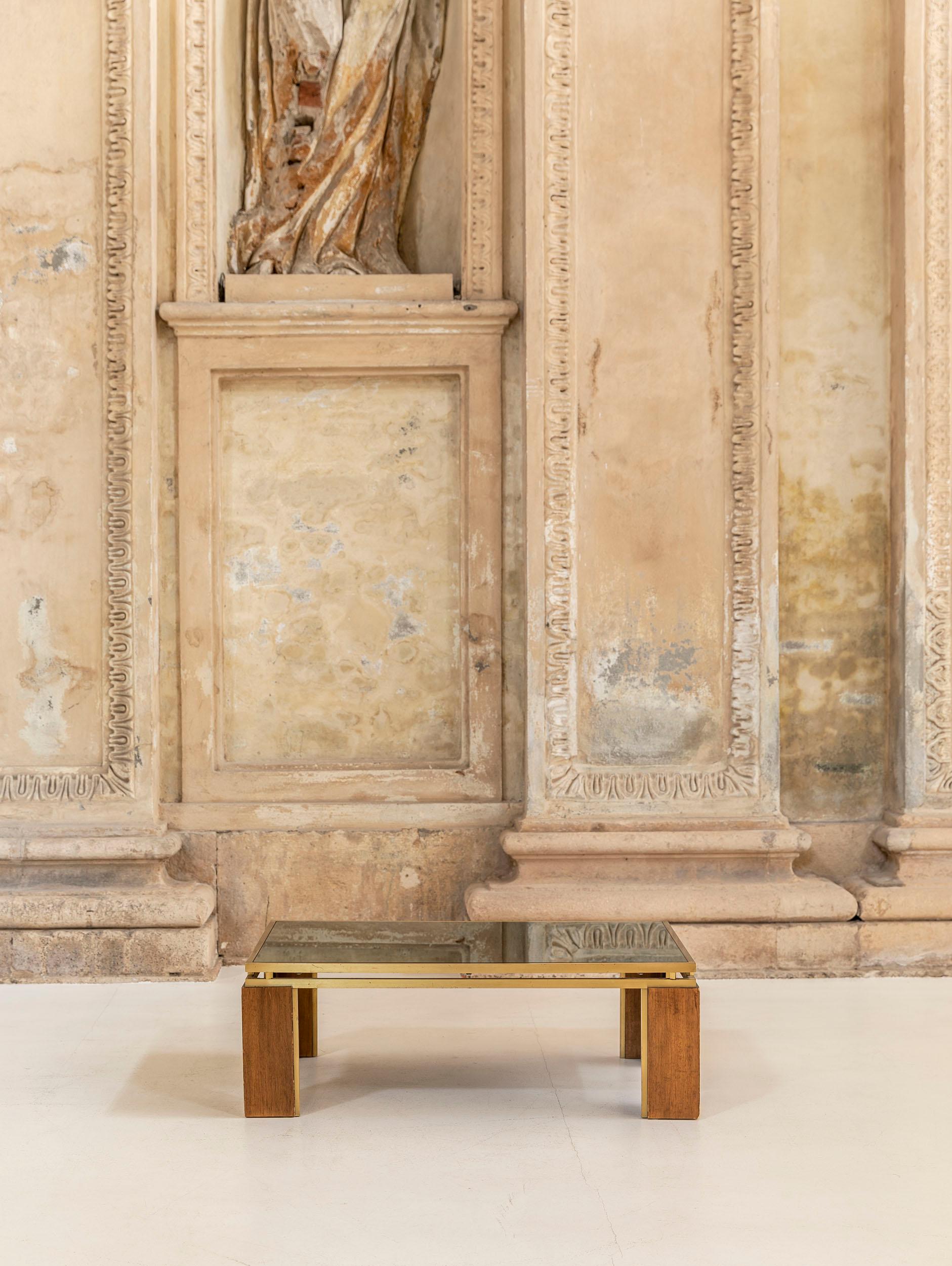 Table basse attribuée à Frigerio. La table a une structure en laiton qui supporte un plateau en miroir fumé et de larges pieds en laiton et en bois.