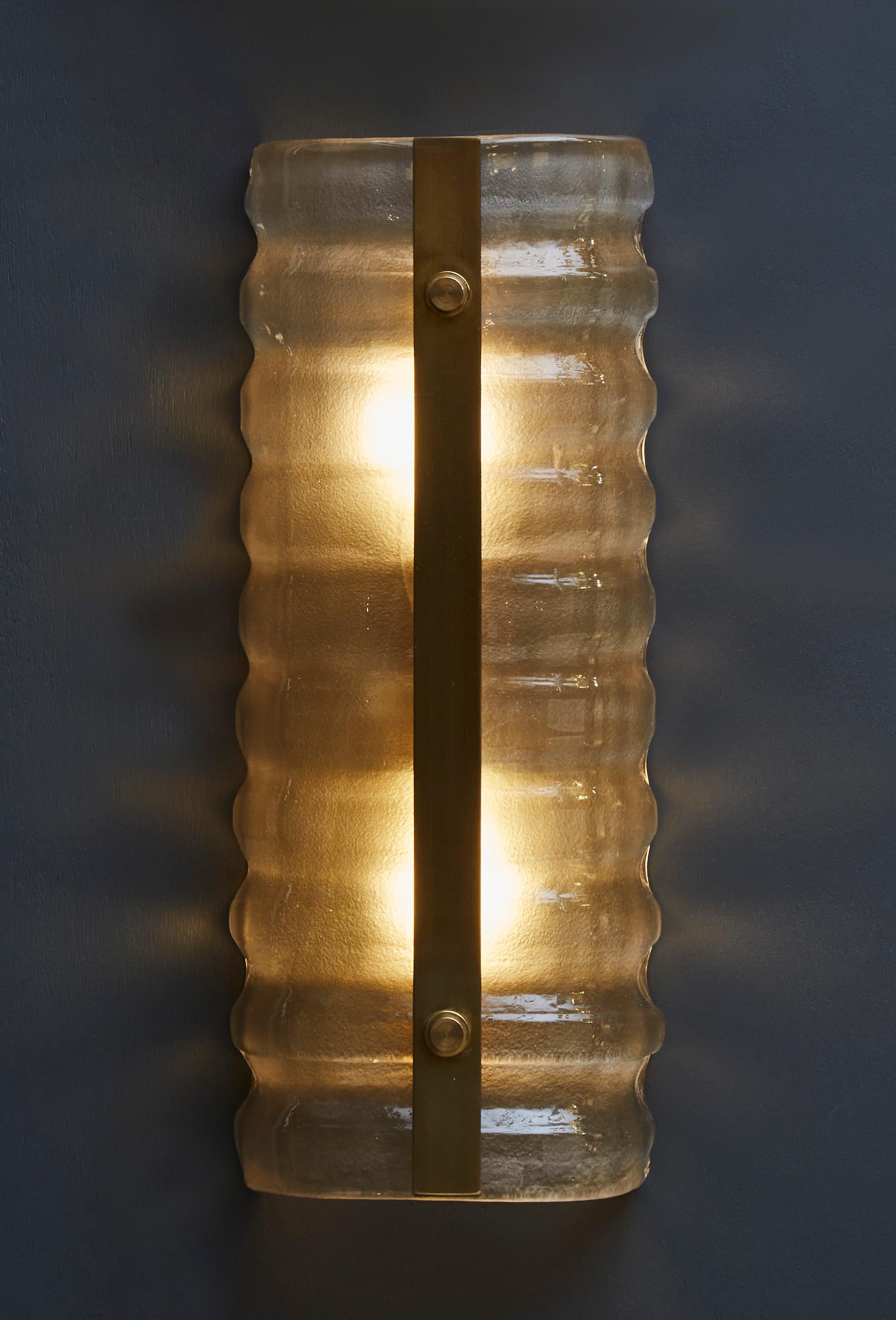 Wall sconces made of a piece of curved and wavy Murano glass with a central brass plate.

Two lights per sconce.

Price per sconce