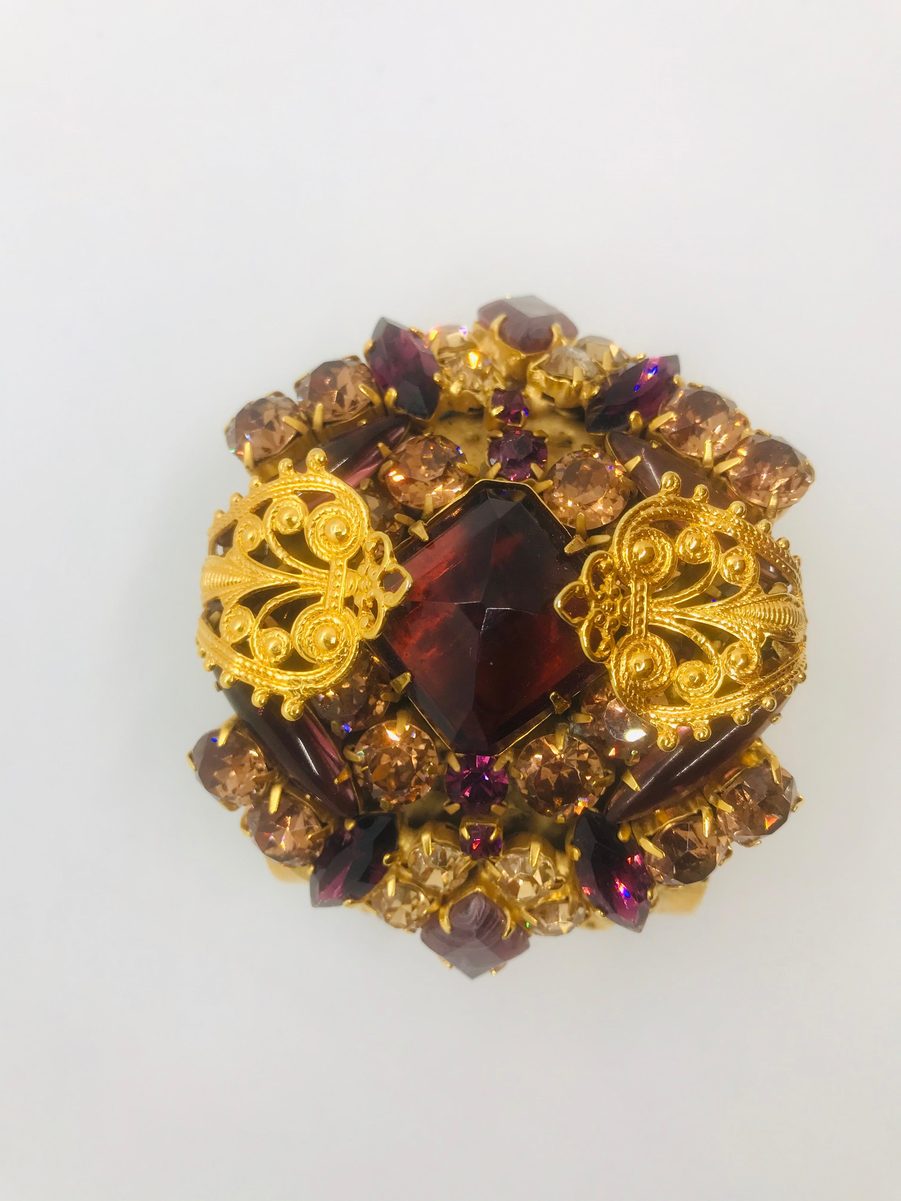 If you love a dramatic bracelet, this smoked topaz and amethyst, Austrian crystal, Byzantine style, open cuff bangle will tick every box.  Ornate gold metal filigree mounts swirl over the top of the jeweled center of this cuff.  A mix of smoked