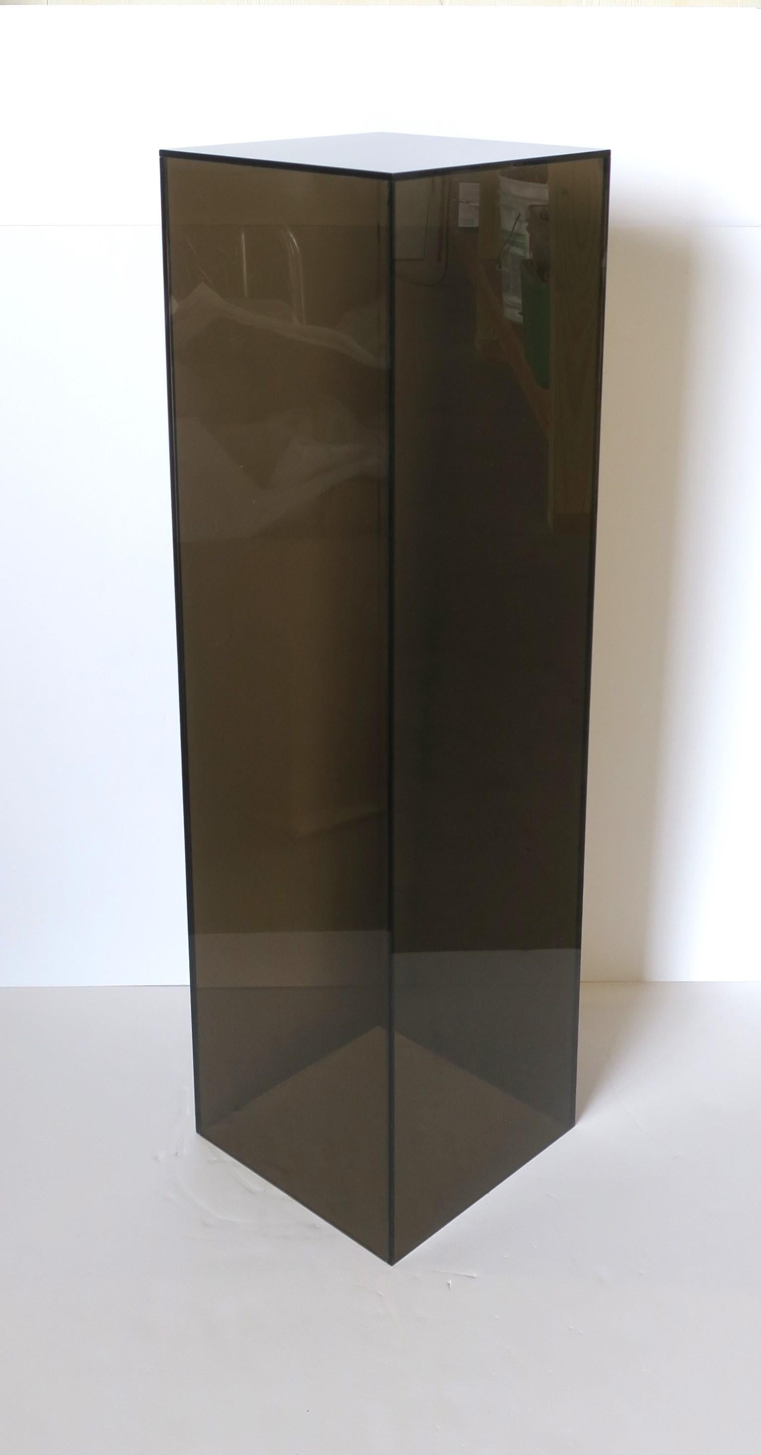 A rectangular smoked black translucent acrylic pedestal column stand, in the modern style, circa late-20th to early 21st century. A great piece to hold or display items such as sculpture, plant, art, jewelry, etc. Very good condition as shown in