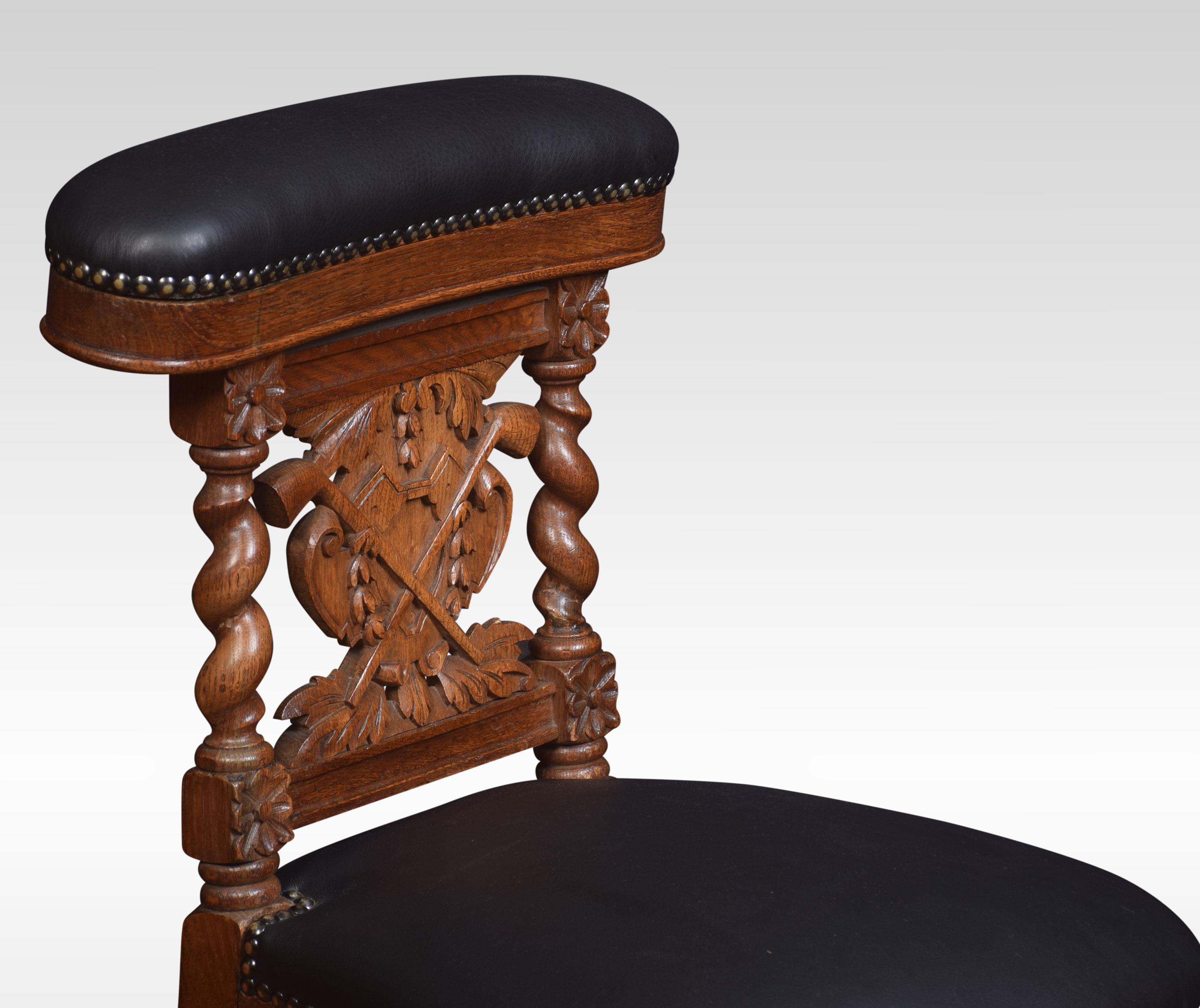 Late 19th century smoker’s carved oak chair, the leather-upholstered hinge back opening to reveal a storage compartment. Above splat back carved with pipes, to the overstuffed seat. All raised up on turned legs united by