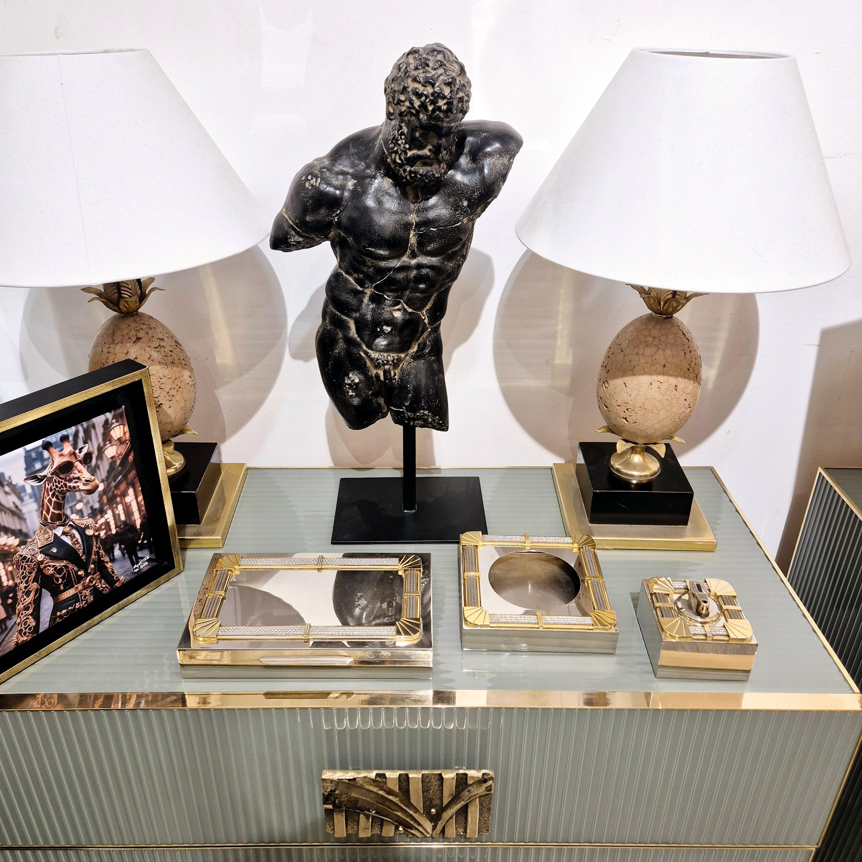 Juego de fumador firmado FRED de la colección Force 10, compuesto por un encendedor, un cenicero y una caja para puros de metal plateado dorado con la típica decoración estilizada de acero trenzado estilo cuerda de la marca. las tres piezas están