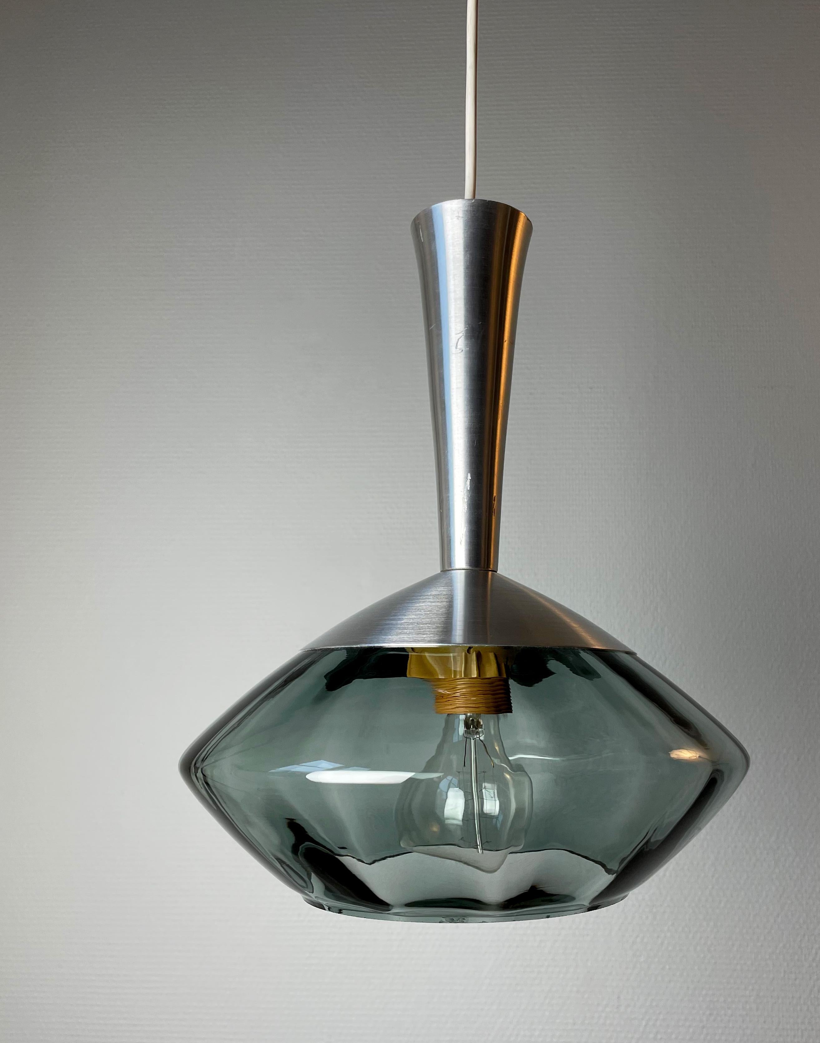 Sleek vintage midcentury modernist blown smokey bluish gray glass and metal pendant manufactured by Swedish Orrefors in the late 1950s. Shiny metal top sits above the glass that is smooth on the outside with subtle vertical lines on the inside.
