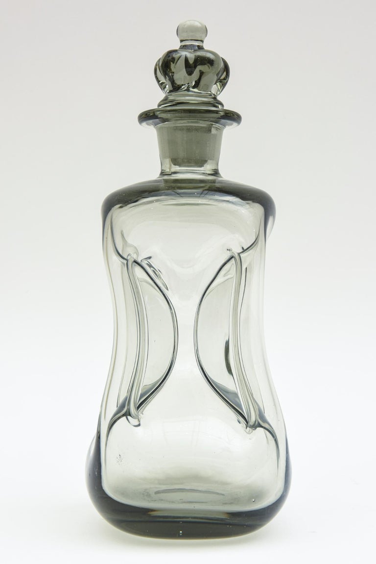 This vintage smokey gray gradient blown glass cinched decanter bottle was designed by Michael Bang for Holmgaard. It is called the Kluk Kluk. He was a major designer for the company. This is from the 60's. What is most unusual about this is the rare