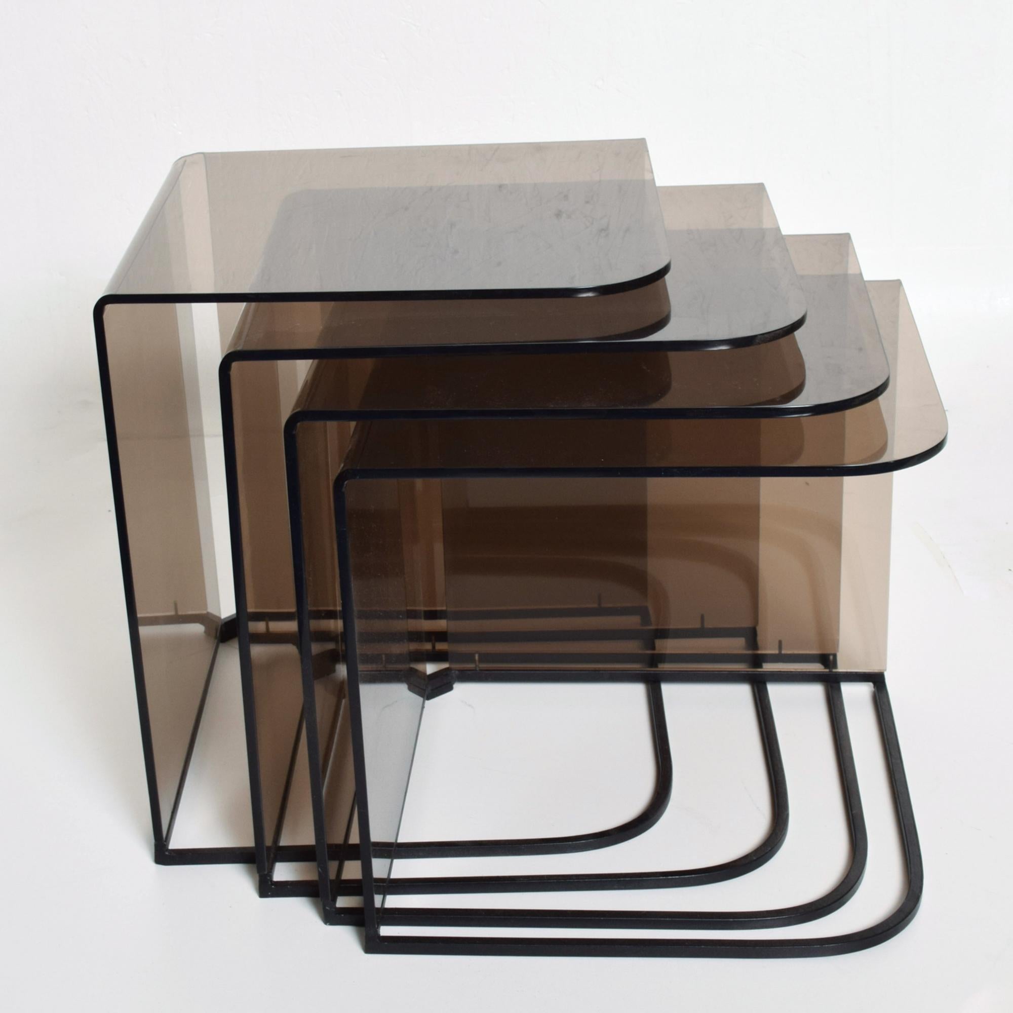 1970s Set of four (4) Nesting Tables Satin Black Metal Iron frame with Smokey Gray Lucite Plexiglass.
Made in the USA circa the 1970s. No maker information present.
Attributed to Charles Hollis Jones.
Largest 18 H x 15.75 x 15.75  #2 16.75 H #3