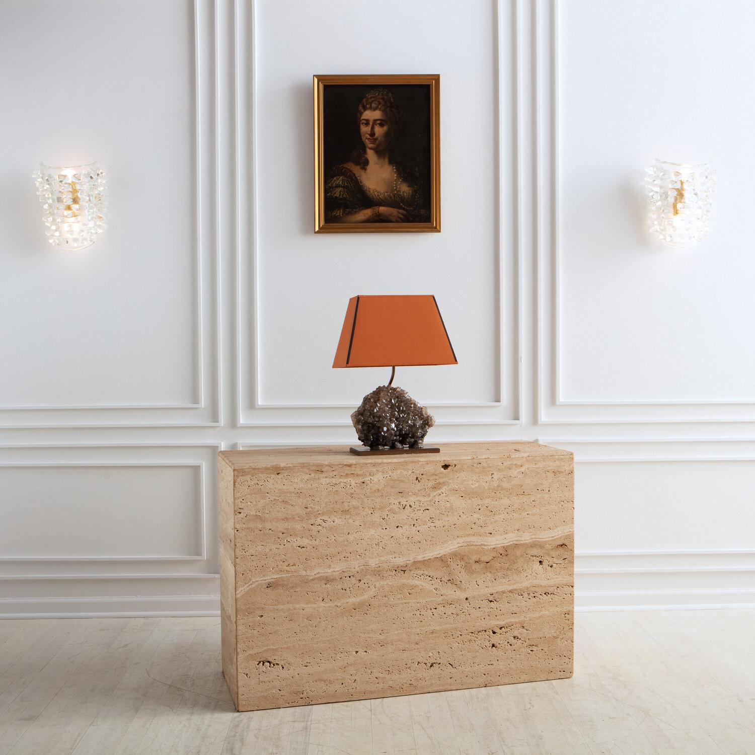A gorgeous Smokey quartz rock table lamp. The large quartz rock specimen is in a brass frame and the lamp features an original lampshade in a lovely terracotta color. Sourced in Belgium. 

 