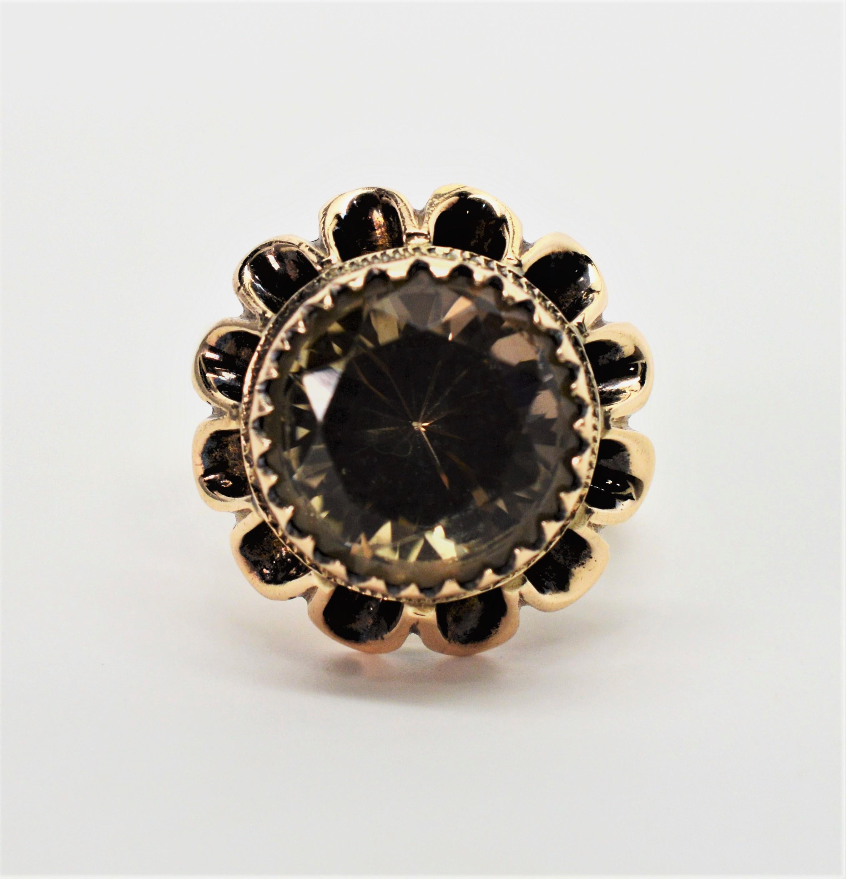 A six carat smoky topaz creates the warm center of this floral burst framed with pretty ten carat 10K yellow gold petals. The fantasy-cut, mocha colored round topaz stone measures 11.5 mm round and is poised in a raised setting presenting a pleasing