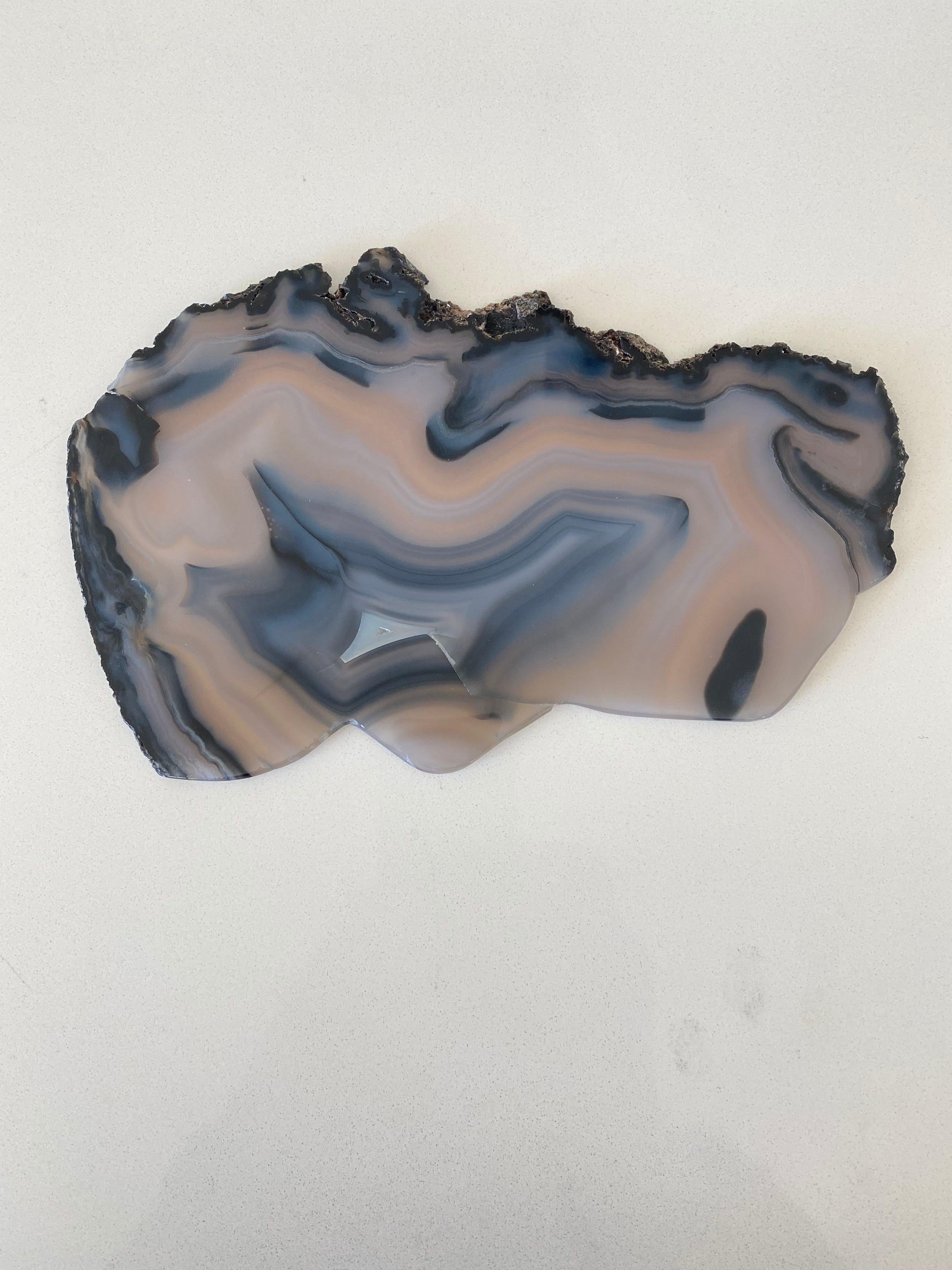 Brazilian thin slice of smoky grey with black agate mounted on a custom steel stand.
Agate is a banded form of finely-grained, microcrystalline Quartz. 
The lovely color patterns and banding make this translucent gemstone very unique. 
Agates can