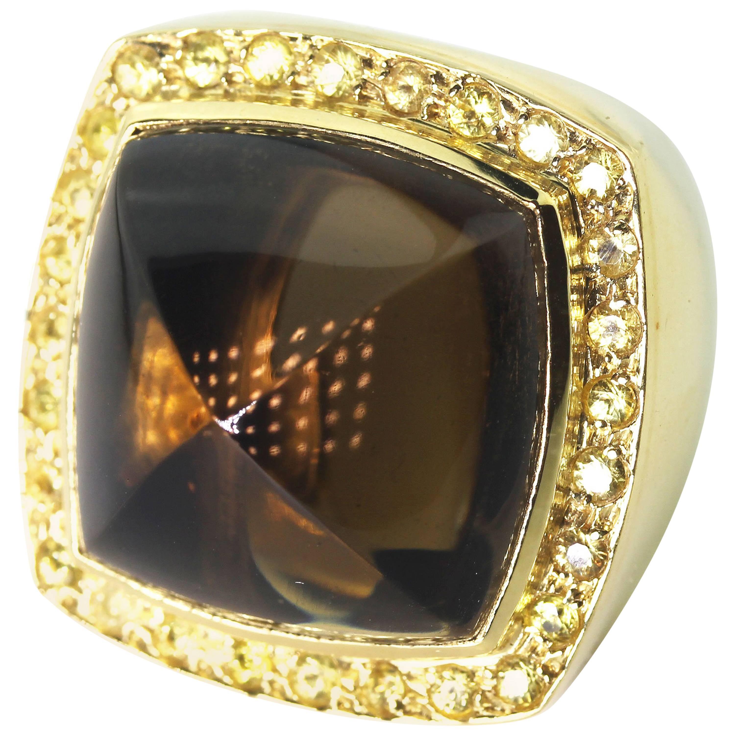 Beautiful huge 18Kt yellow gold ring set with large 32.4 carat Smoky Quartz enhanced with sparkling beautiful 2.5 carats brilliant yellow Sapphires.  This unique handmade ring is a size 7 (sizable). The Smoky Quartz measures 20 mm x 20 mm and the