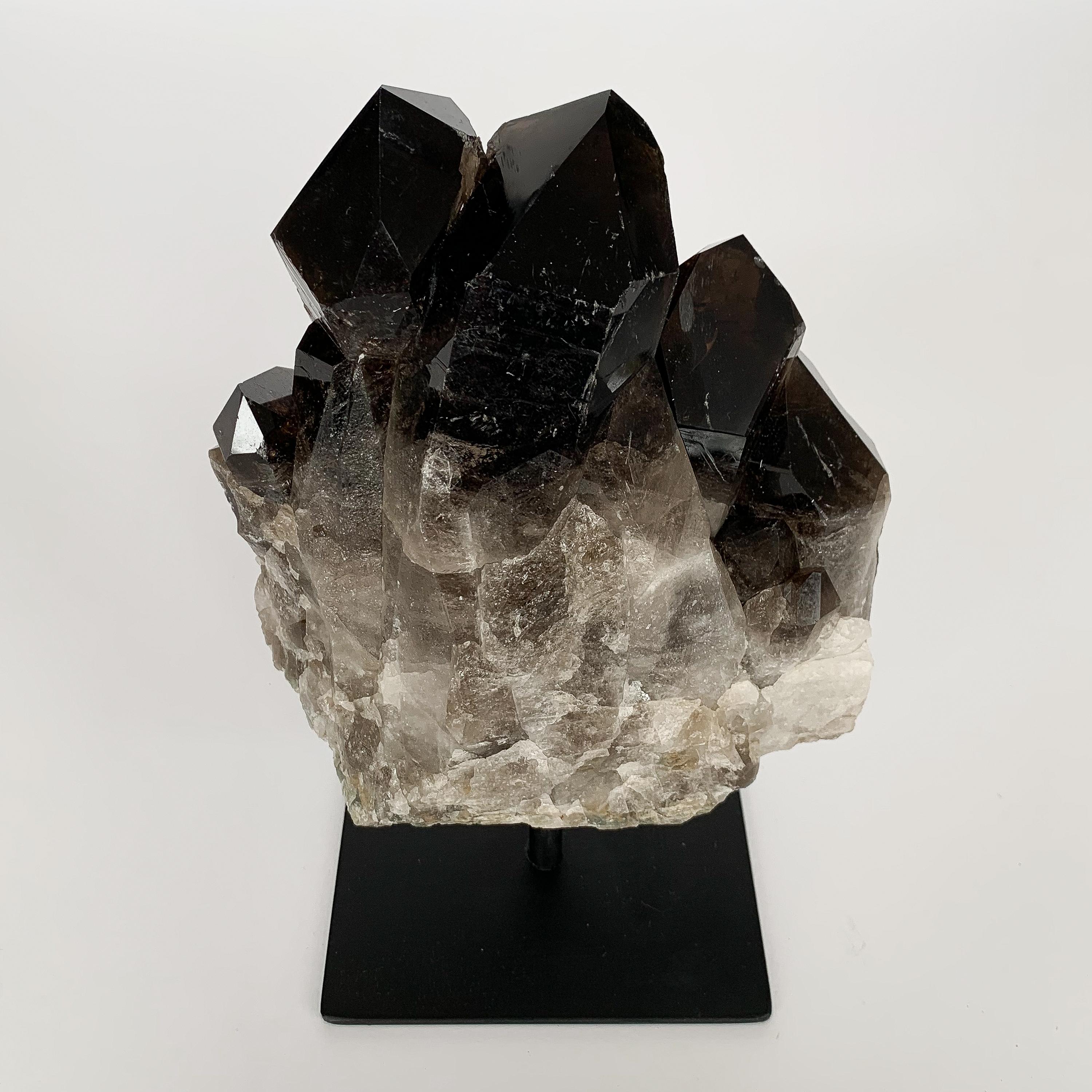 Natural smoky quartz crystal specimen mounted to a painted black metal stand. Measures: 9