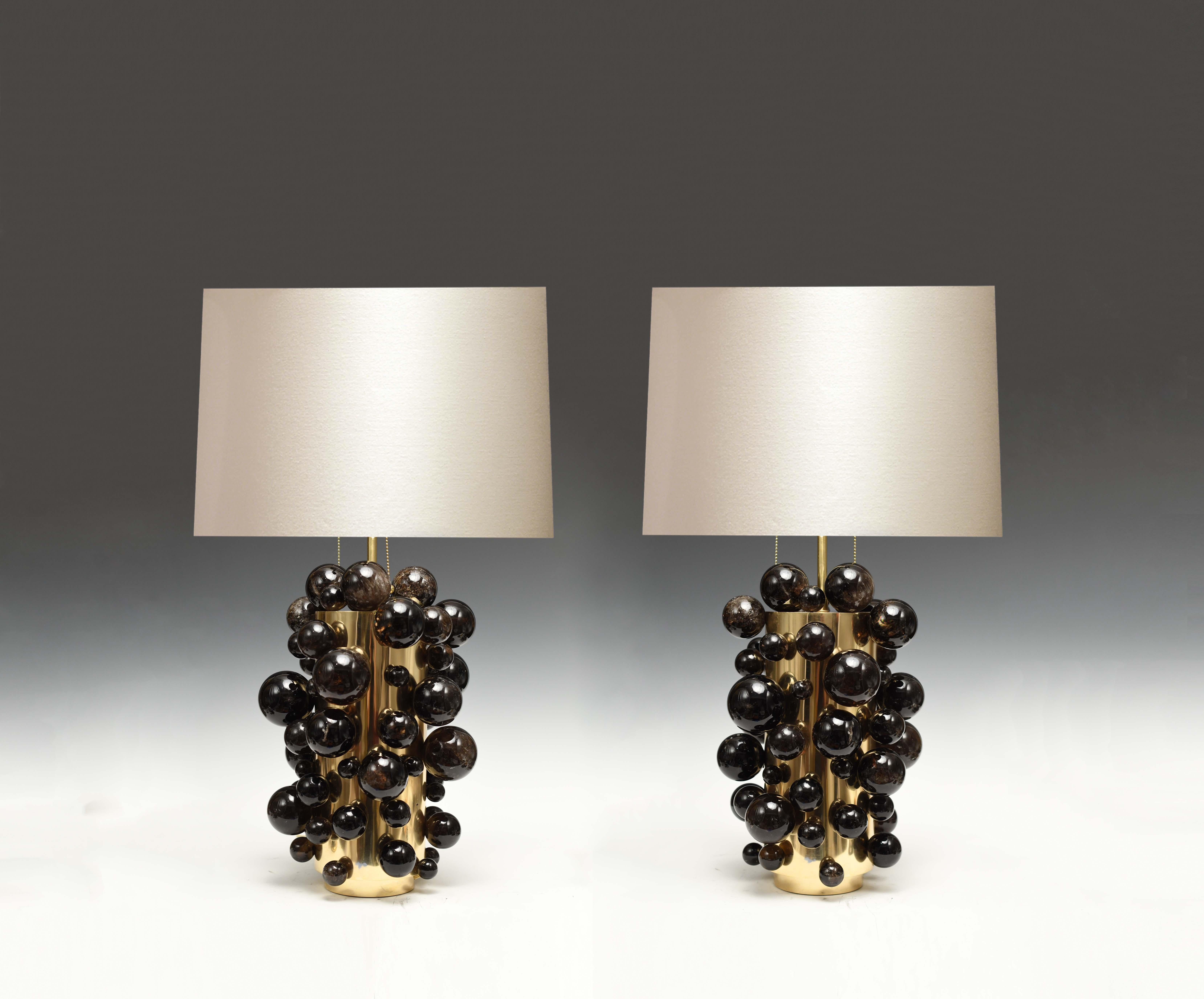 A pair of luxury smoky rock crystal quartz bulb lamps with polished brass bases, created by Phoenix Gallery, NYC. To the top of the rock crystal 17 inch. Lampshade not included.