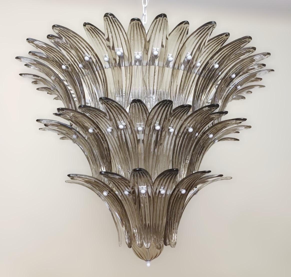 Lustre Palmette italien avec des feuilles en verre Murano fumé disposées sur trois niveaux et montées sur un cadre en métal blanc / Made in Italy by Fabio LTD
Diamètre : 31,5 pouces / Hauteur : 23,5 pouces plus la chaîne et le baldaquin
9 lampes /