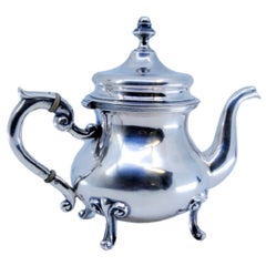Smooth silver coffee pot w/ 4 exposed feet, lid w/ knob 
standing on 4 feet