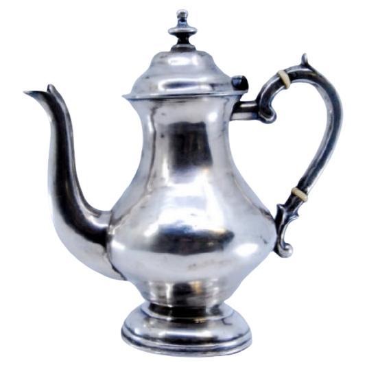 Caffettiera d
argento liscia con un pomello sul coperchio e appoggiata su una base rotonda
