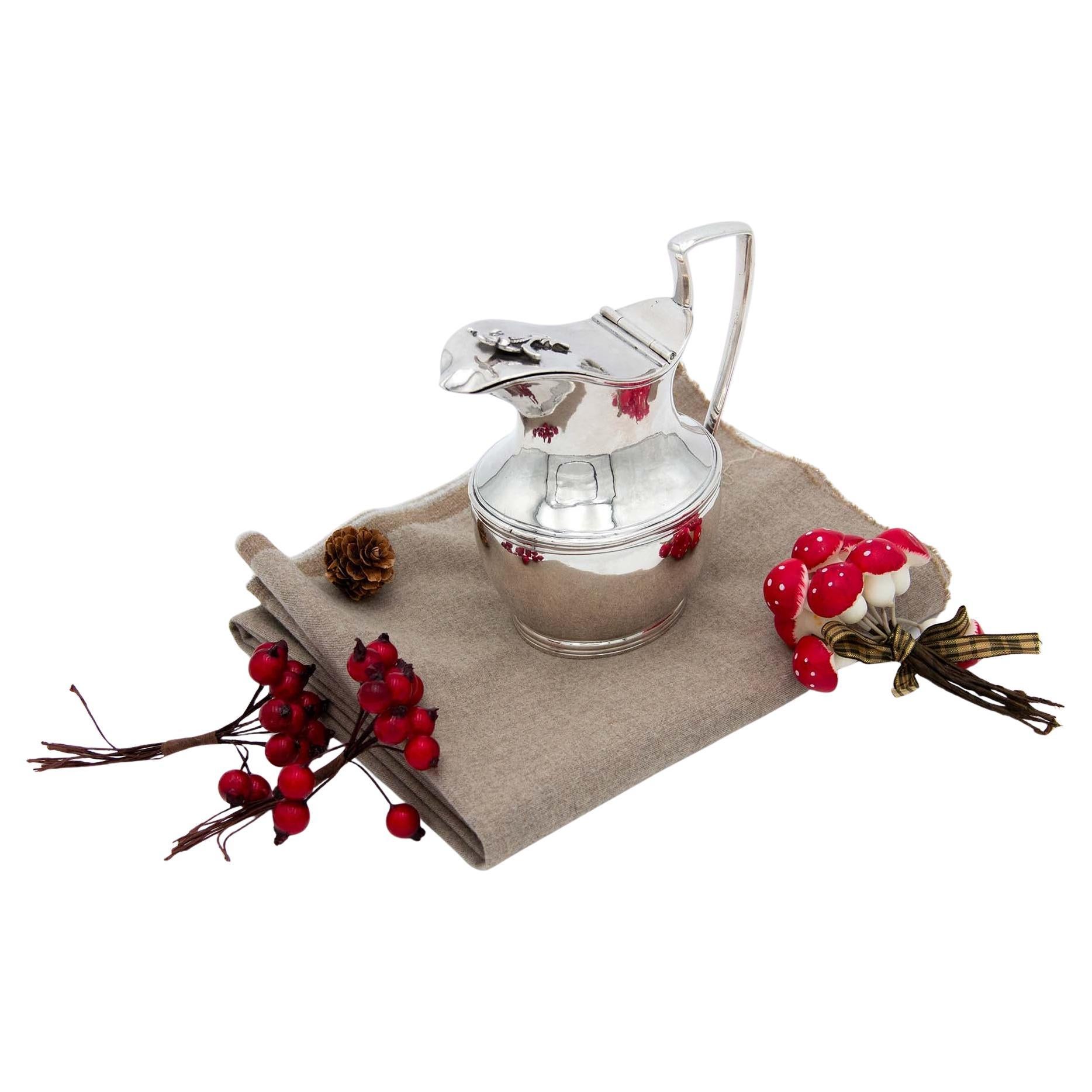 Smooth silver milk jug w/ surrounding trim & floral motifs on the lid as a knob