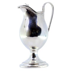 Smooth silver milk jug with knob on the hinged lid and base with friezes