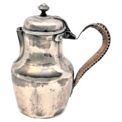 Smooth silver milk jug with straw handle and knob on the hinged lid
