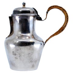 Smooth silver milk jug with straw handle and knob on the hinged lid