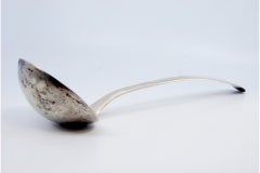 Smooth silver soup ladle with a strip along the handle