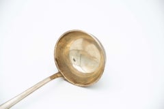 Smooth silver soup ladle with a trim on the shell