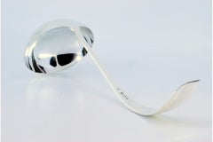 Smooth silver soup ladle with grooves along the curved handle