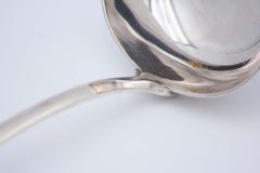 Smooth silver soup ladle with reliefs along the handle