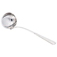 Smooth silver soup ladle with reliefs along the handle