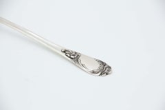 Smooth silver soup ladle with reliefs on the handle