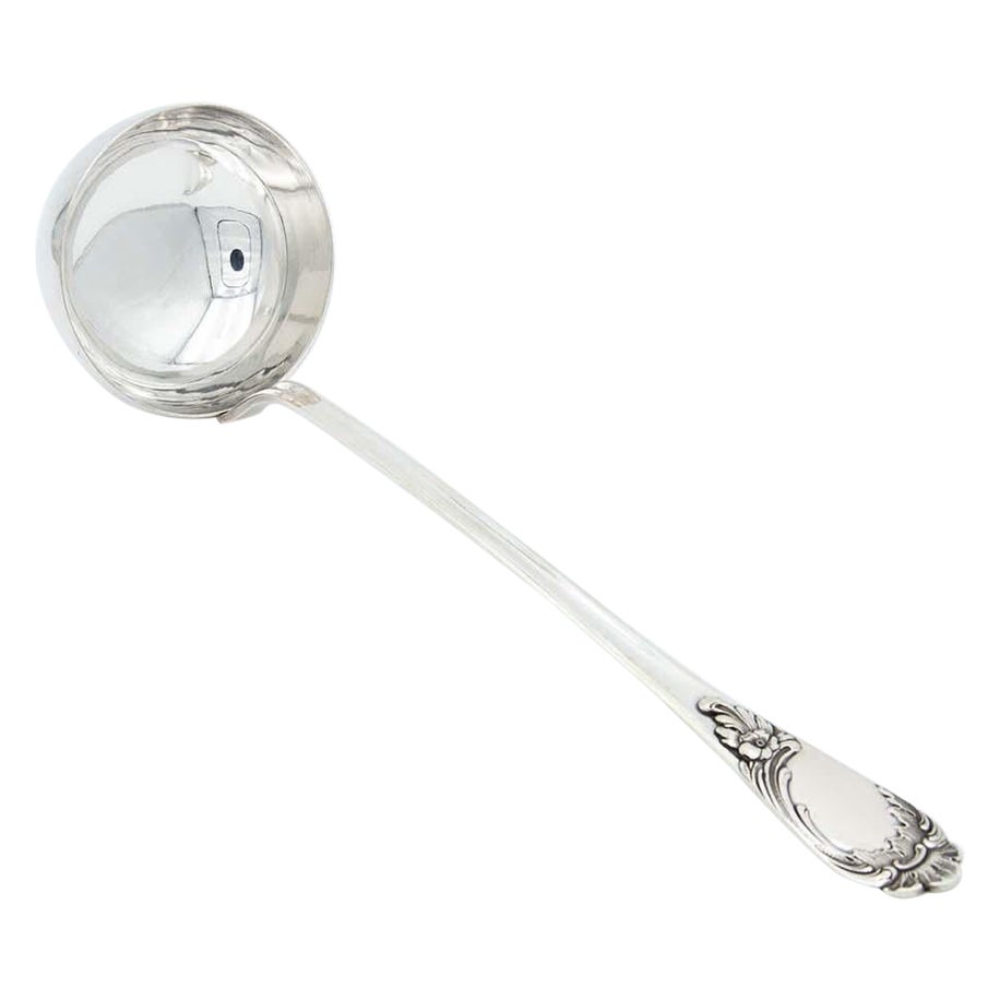 Smooth silver soup ladle with reliefs on the handle