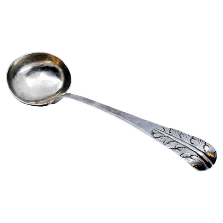 Smooth silver soup ladle with reliefs on the handle